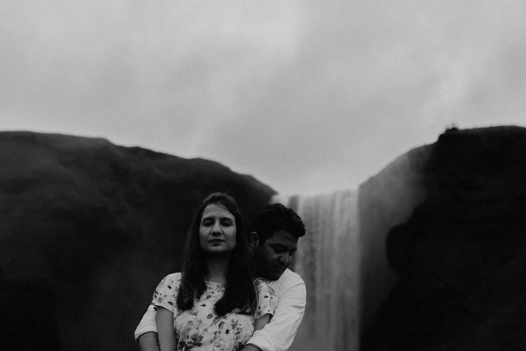Couple holding hands in front of Skógafoss during a Lovers Session in Iceland