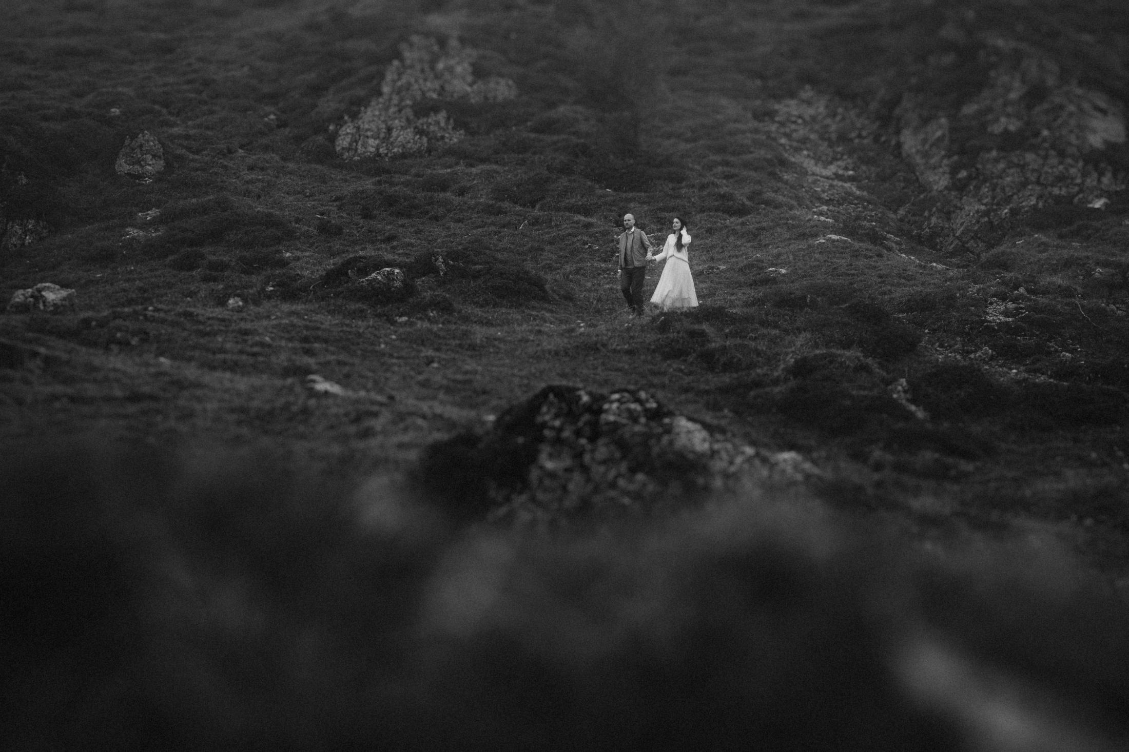 Black-and-white view of the couple among rocks and low cloud.