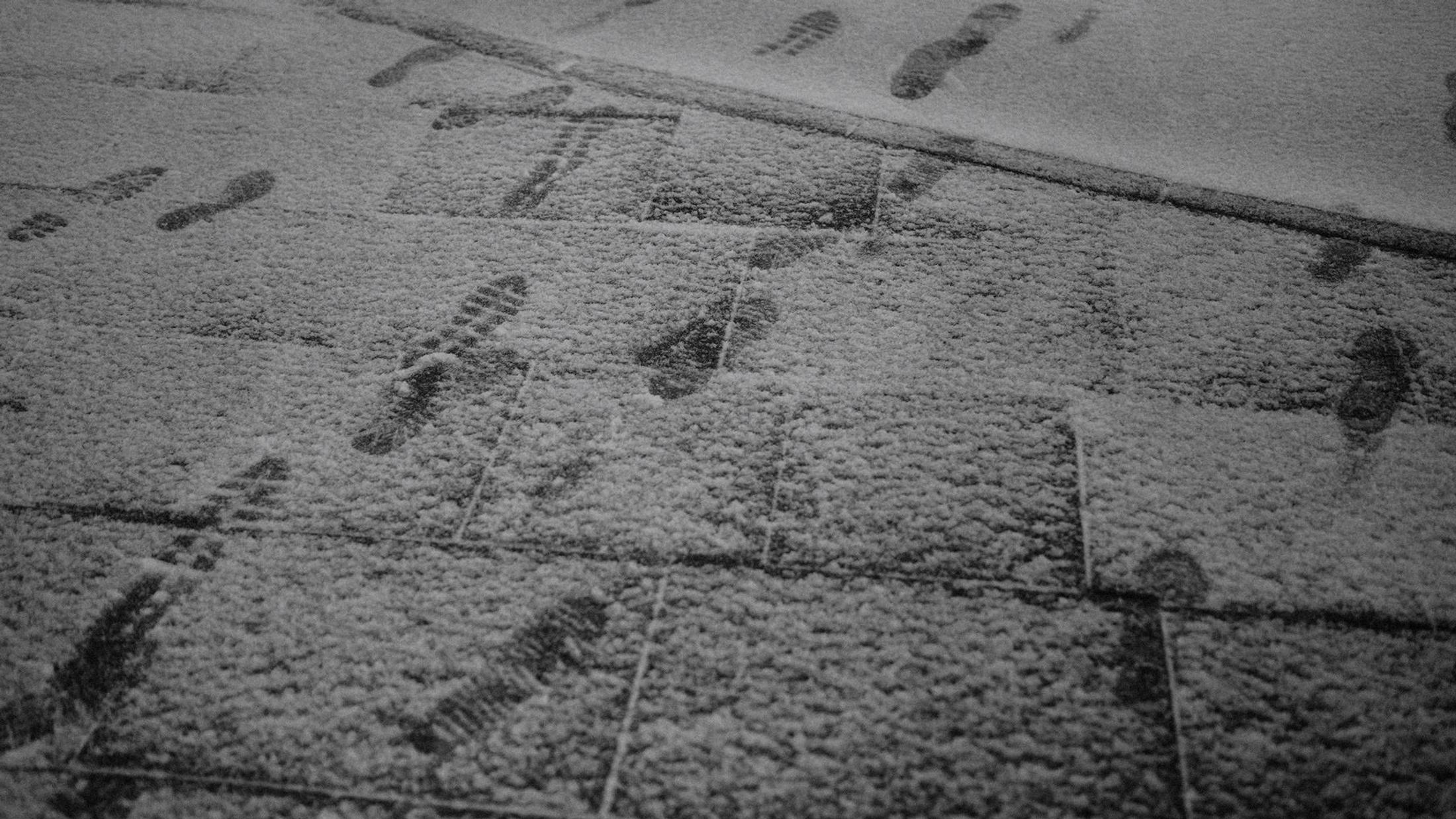 Overlapping footprints mark fresh snow on a Hamburg pavement.