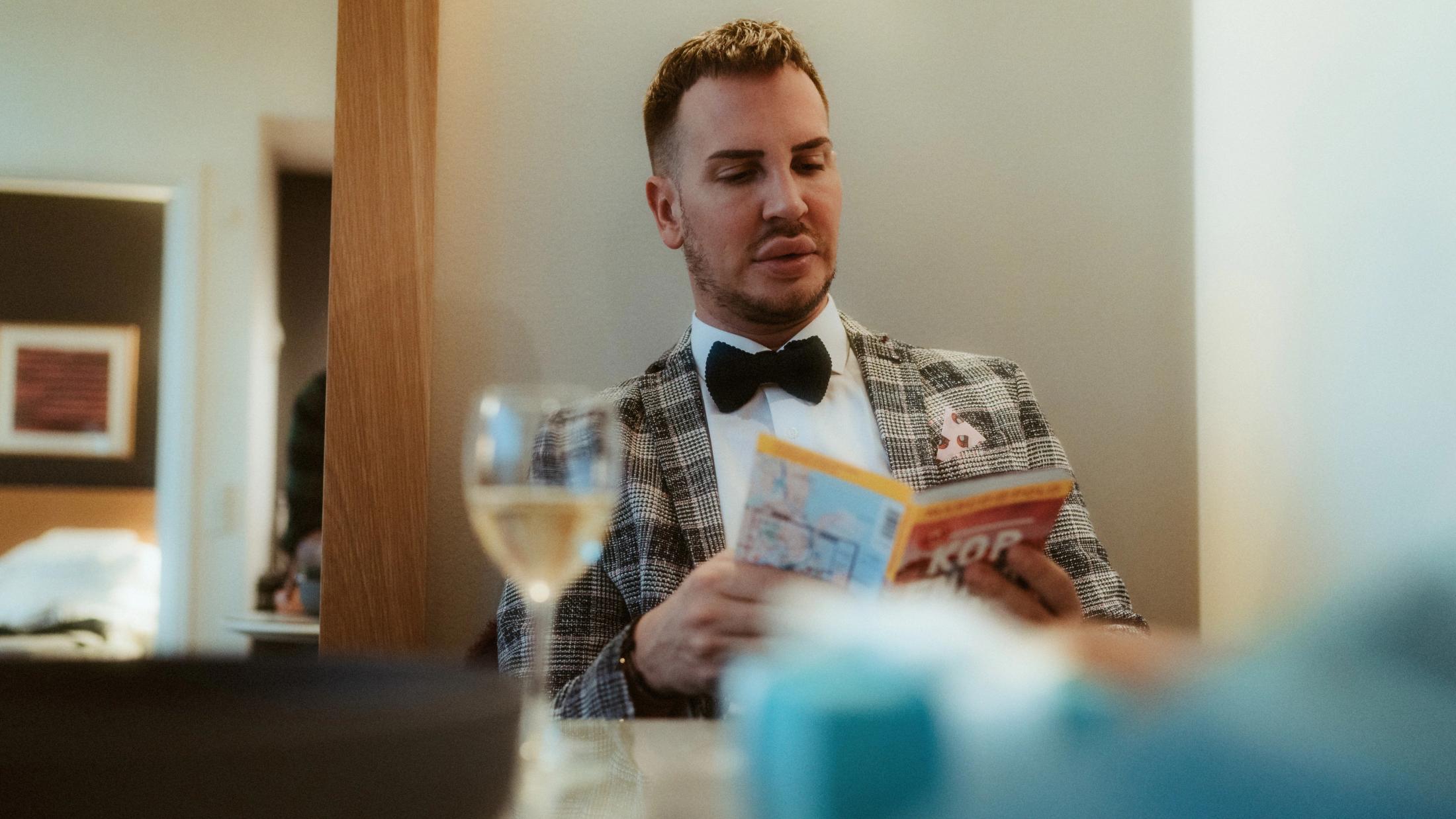Pia reading at the table in a white shirt and bow tie