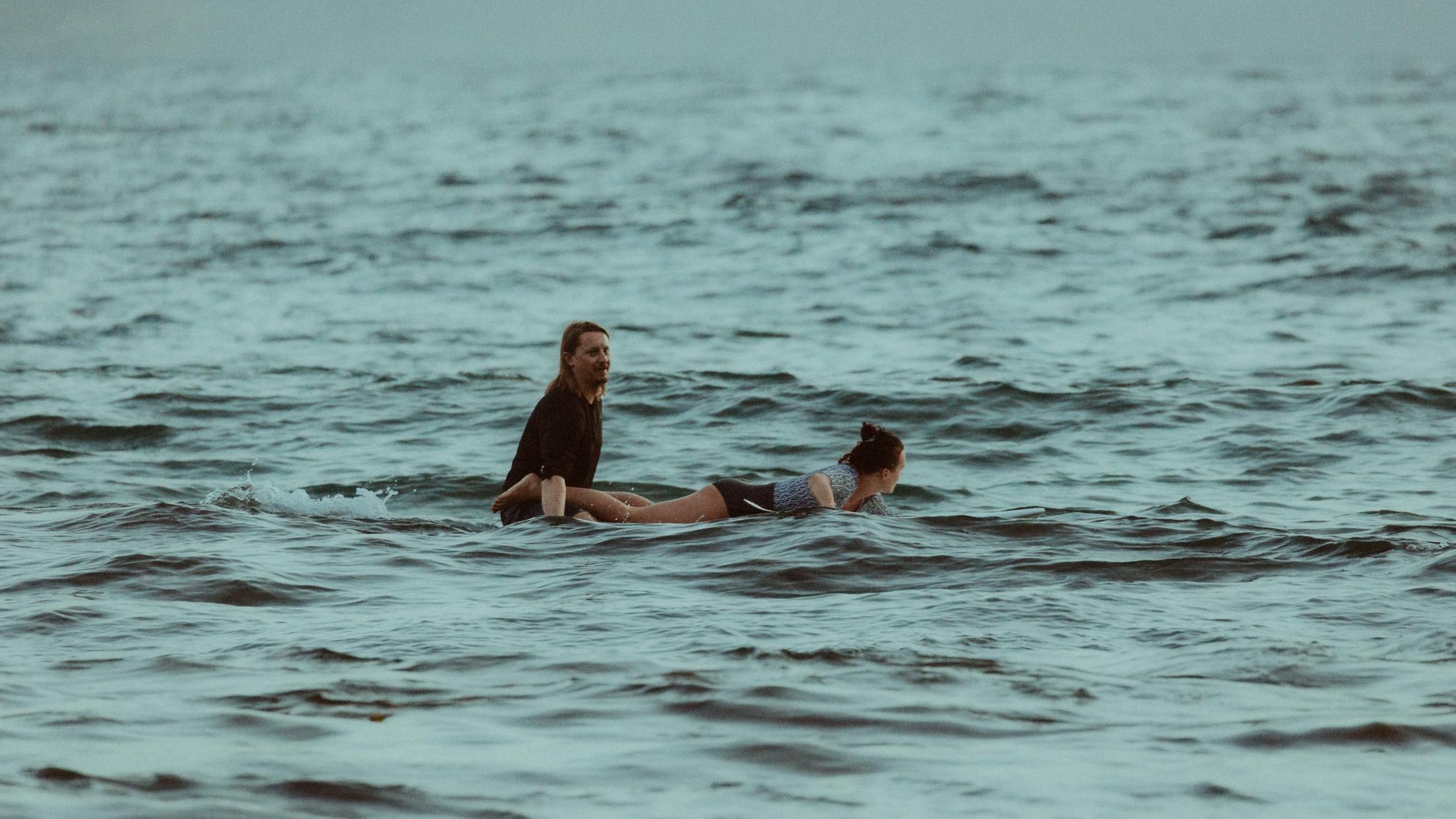 Roman paddling while Petra lies on a surfboard in open water