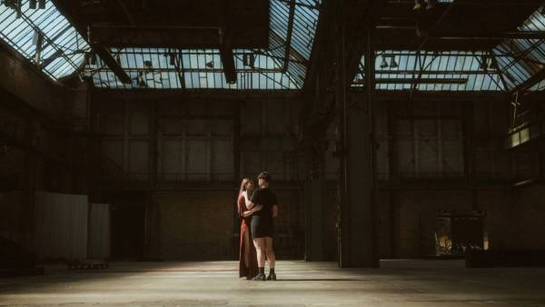 Noah and Michèle embracing at the center of the enormous dark Mahalla hall.