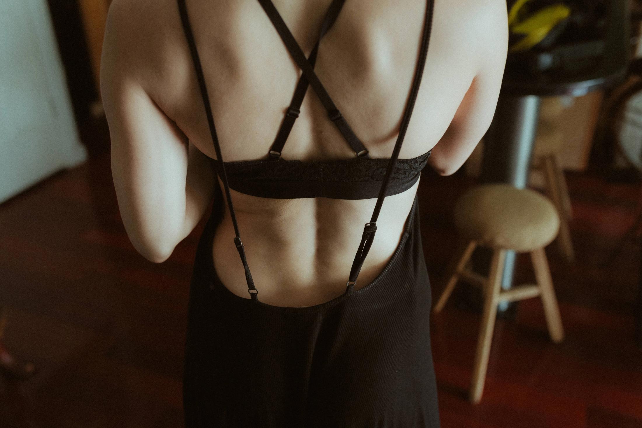 Close view of the straps and lines of Maya’s black lingerie from behind.