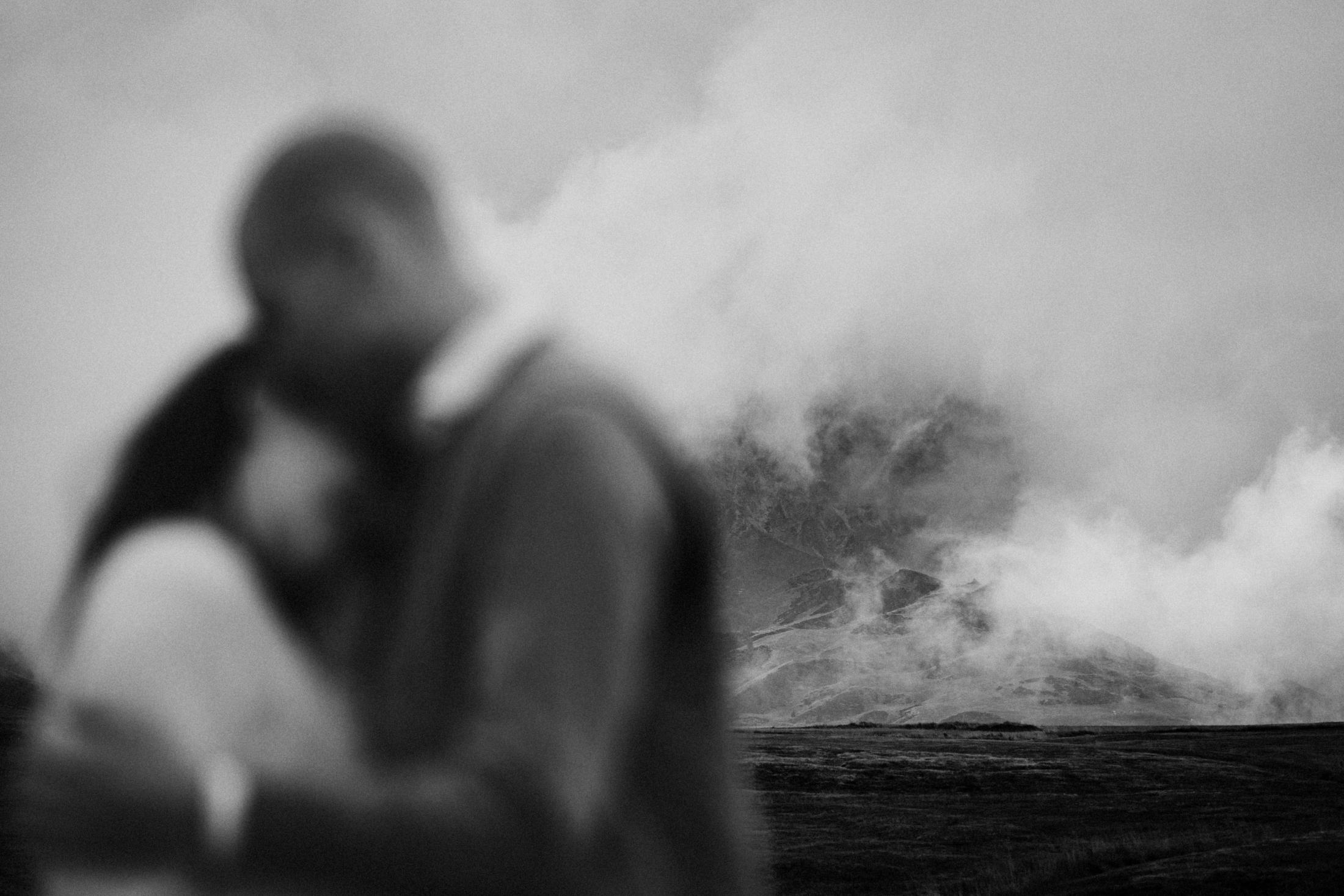 Soft-focus view of the couple embracing with clouds behind them.
