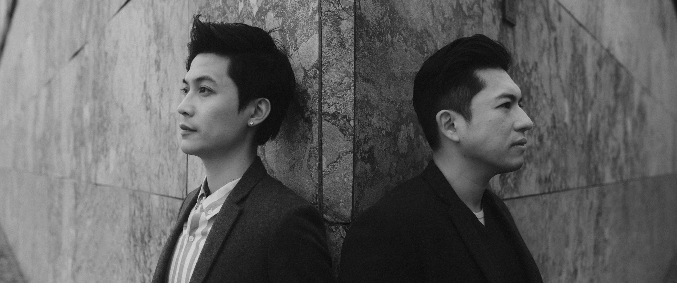 Two black-and-white portraits show Kevin and Terence against a stone wall.