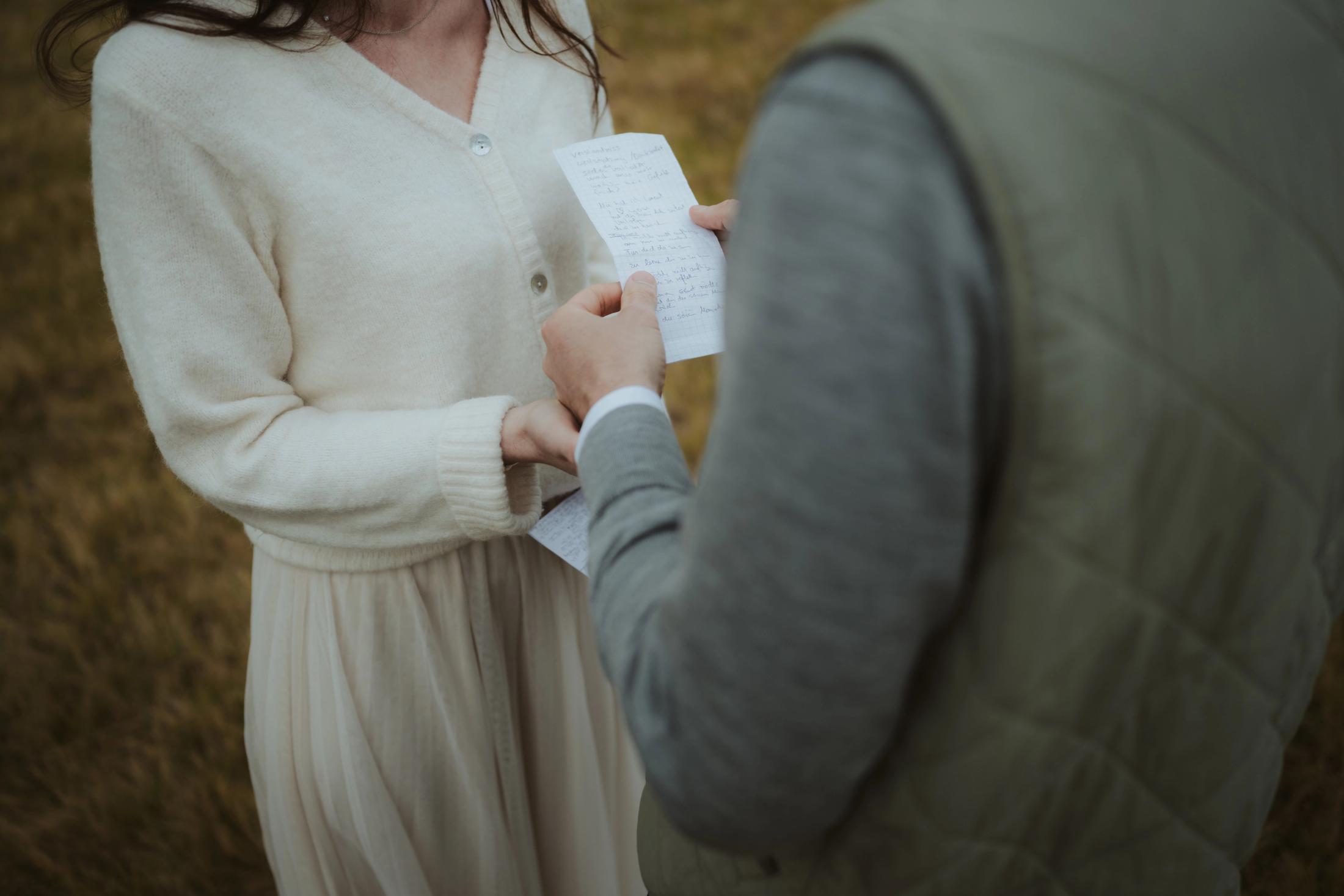 Close view of hands holding a folded handwritten vow letter.