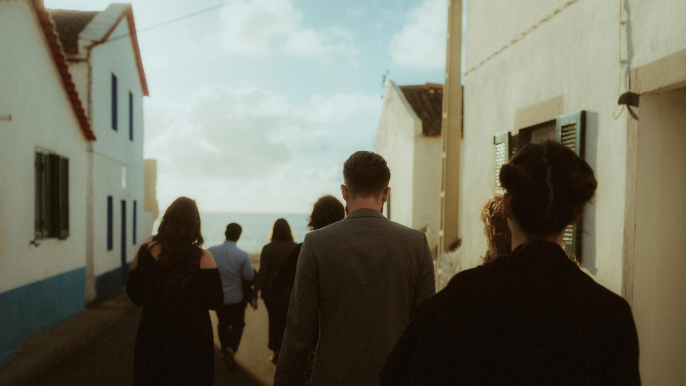 A line of people descends a path toward the black-sand beach.