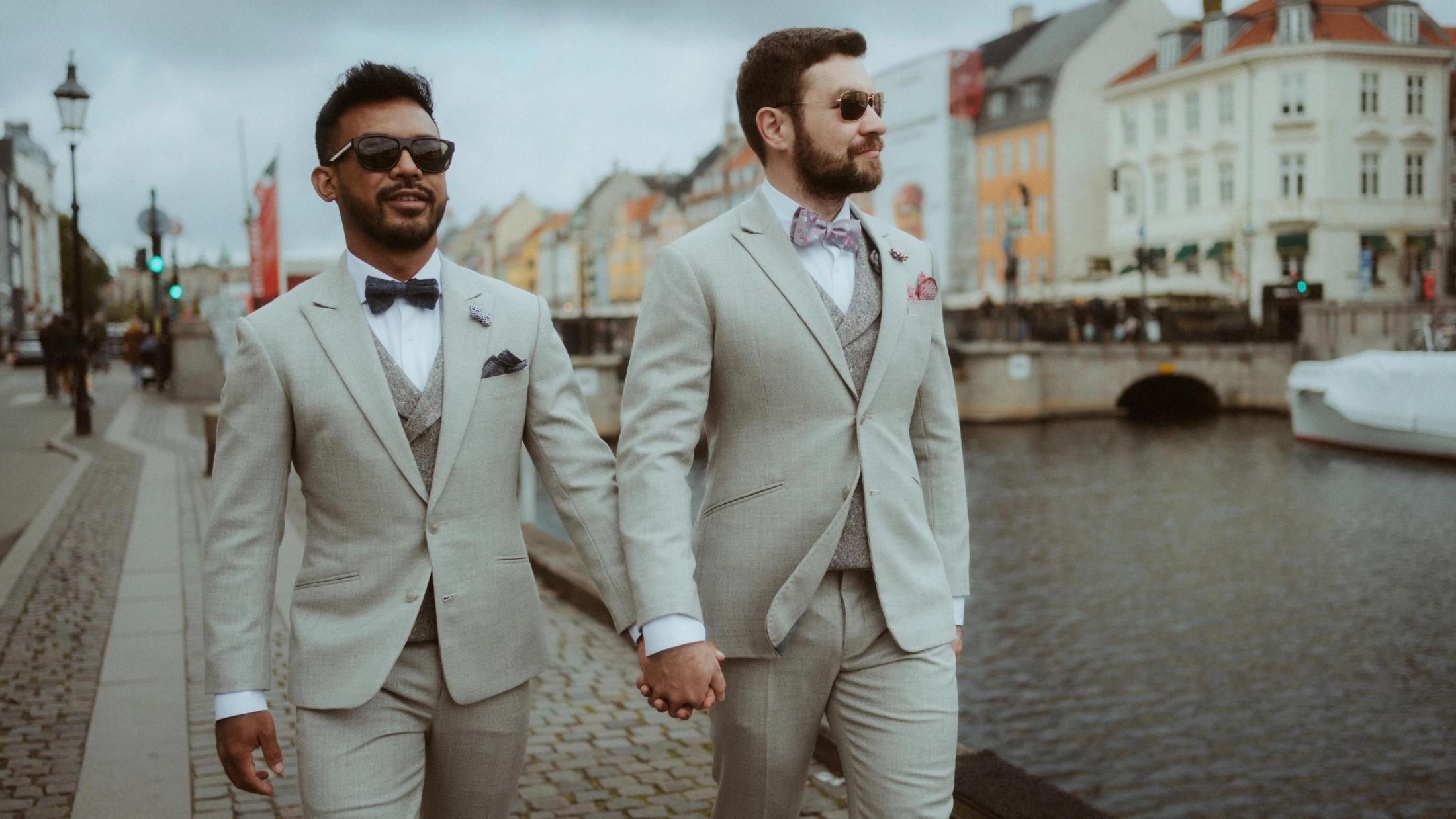 Kris and Ilya walk hand in hand beside the water at Nyhavn.