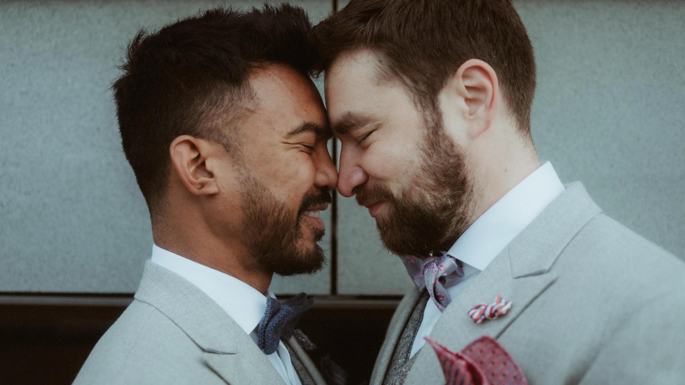 Kris and Ilya laugh with their foreheads touching in a close street portrait.