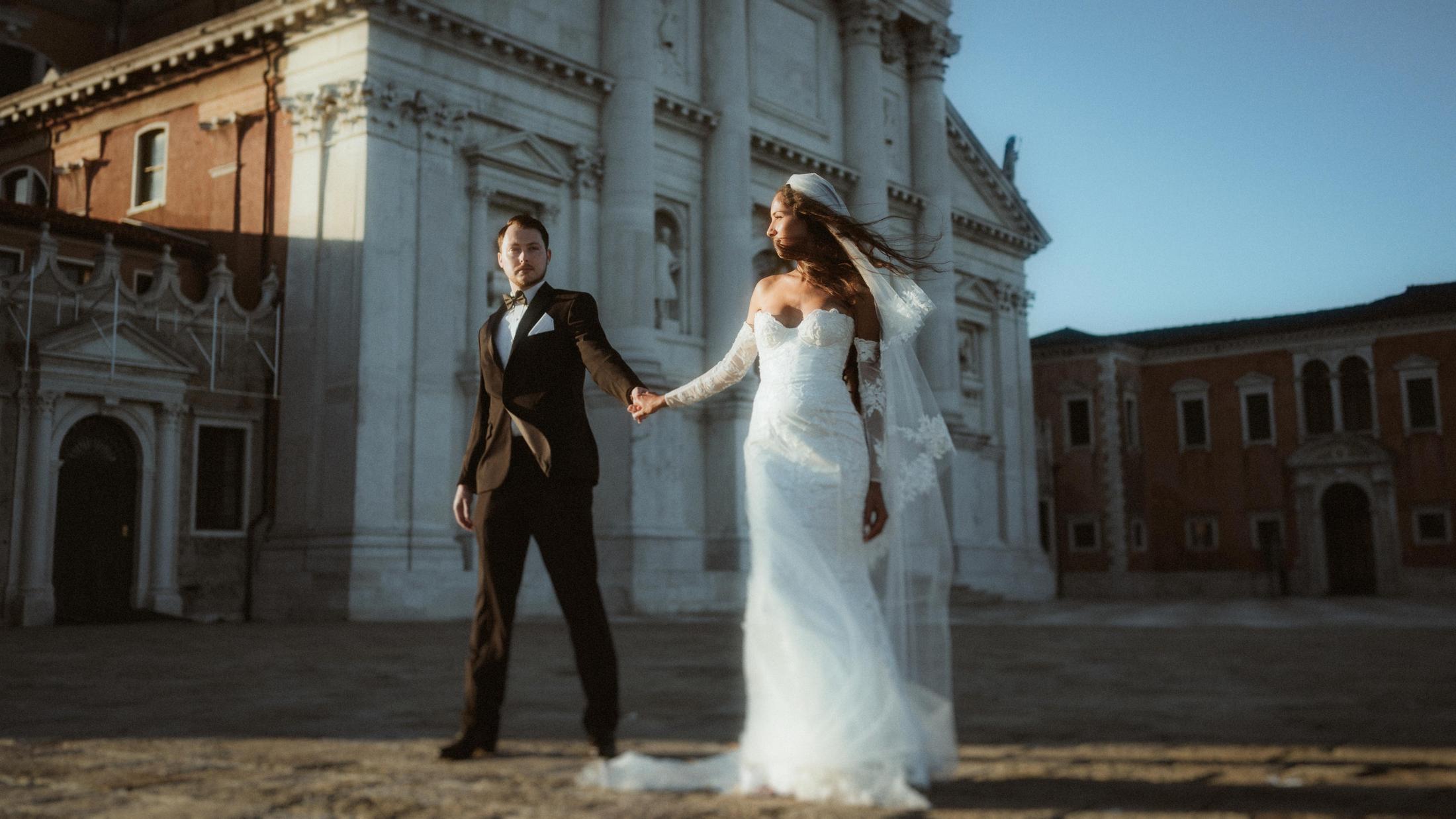 The couple moves across a Venetian square in front of a white church facade.