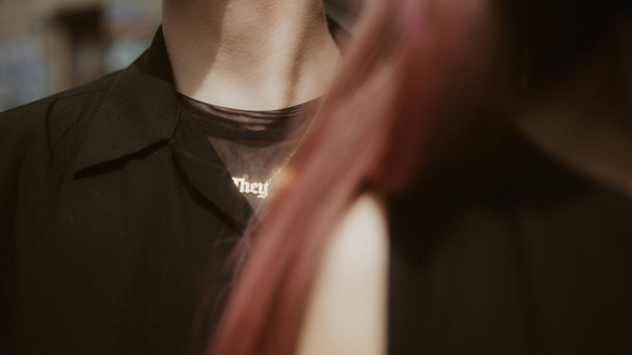 Noah's They necklace framed between Noah and Michèle's bodies as they embrace.