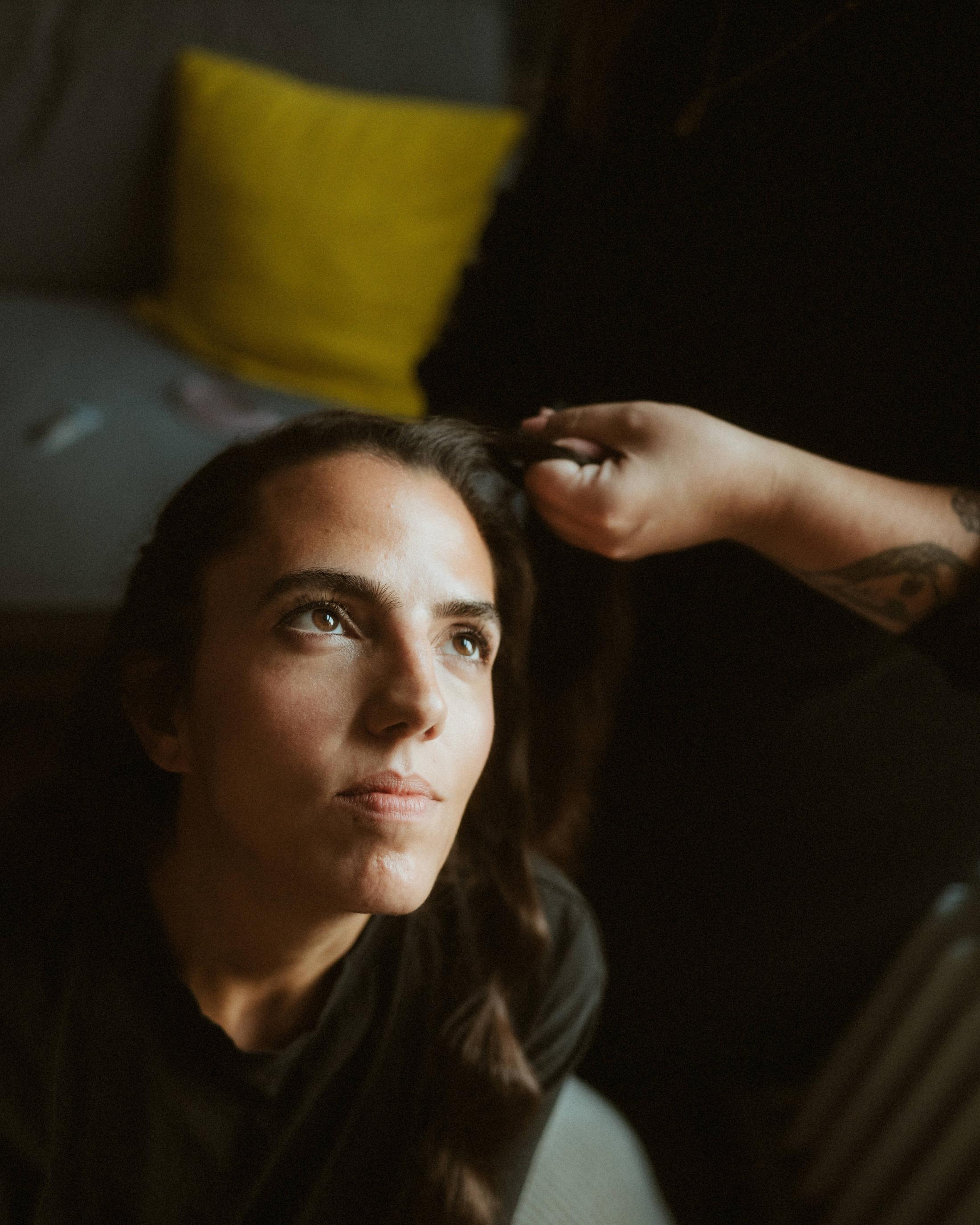 Laura seated while another person reaches toward her hair