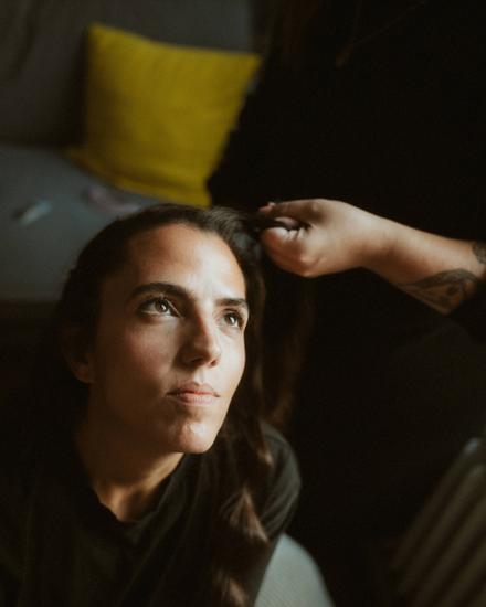 Laura seated while another person reaches toward her hair