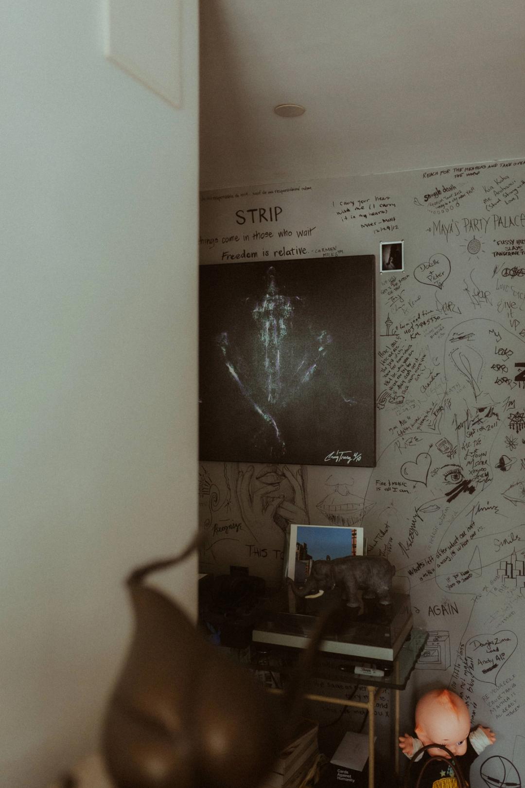 A quiet corner of Maya’s apartment with artwork and a wooden chair.