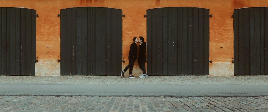 The second groom stands against the same orange Copenhagen wall.