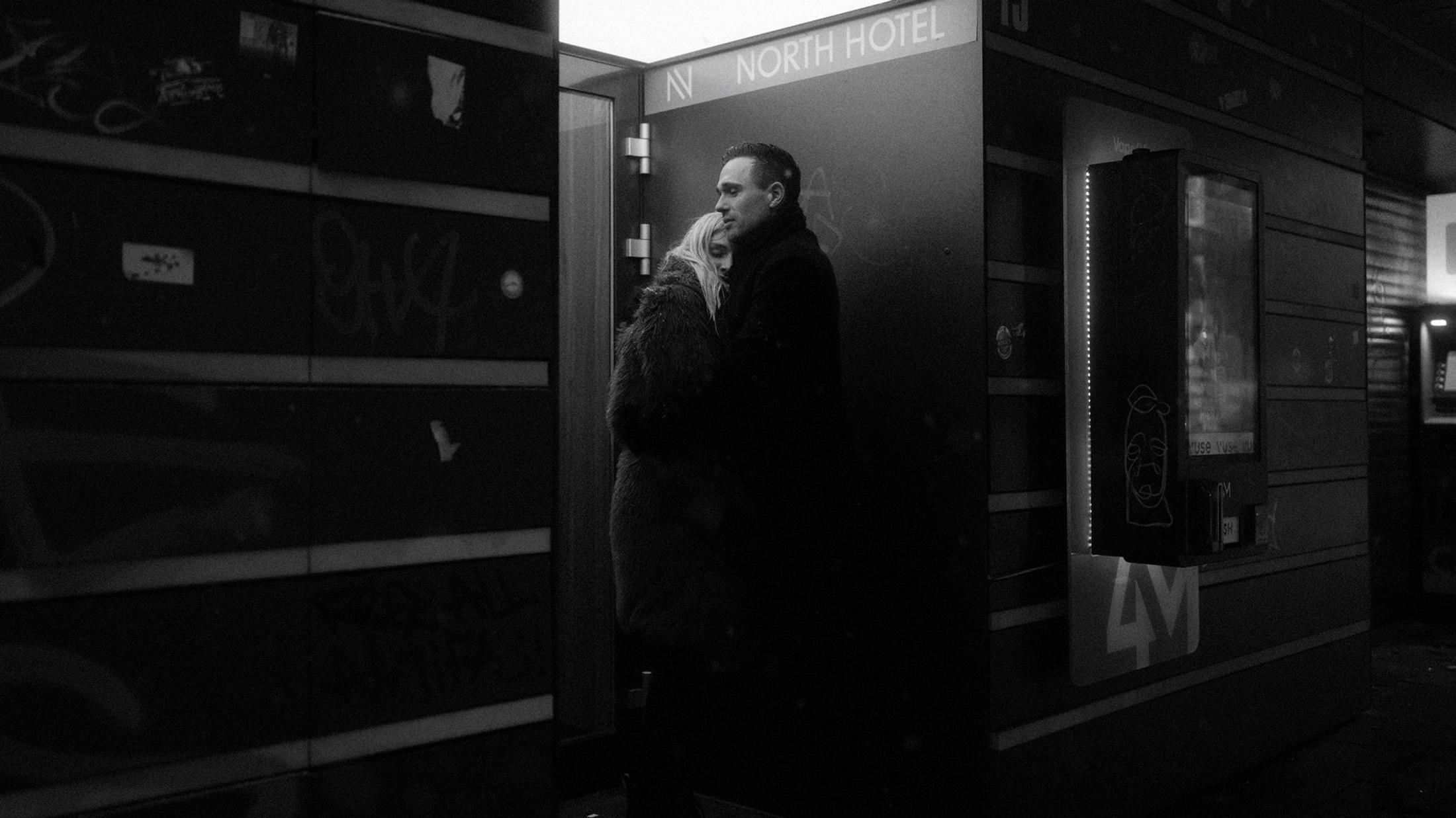 Lorelai and Steffen embrace outside a St. Pauli station entrance at night.