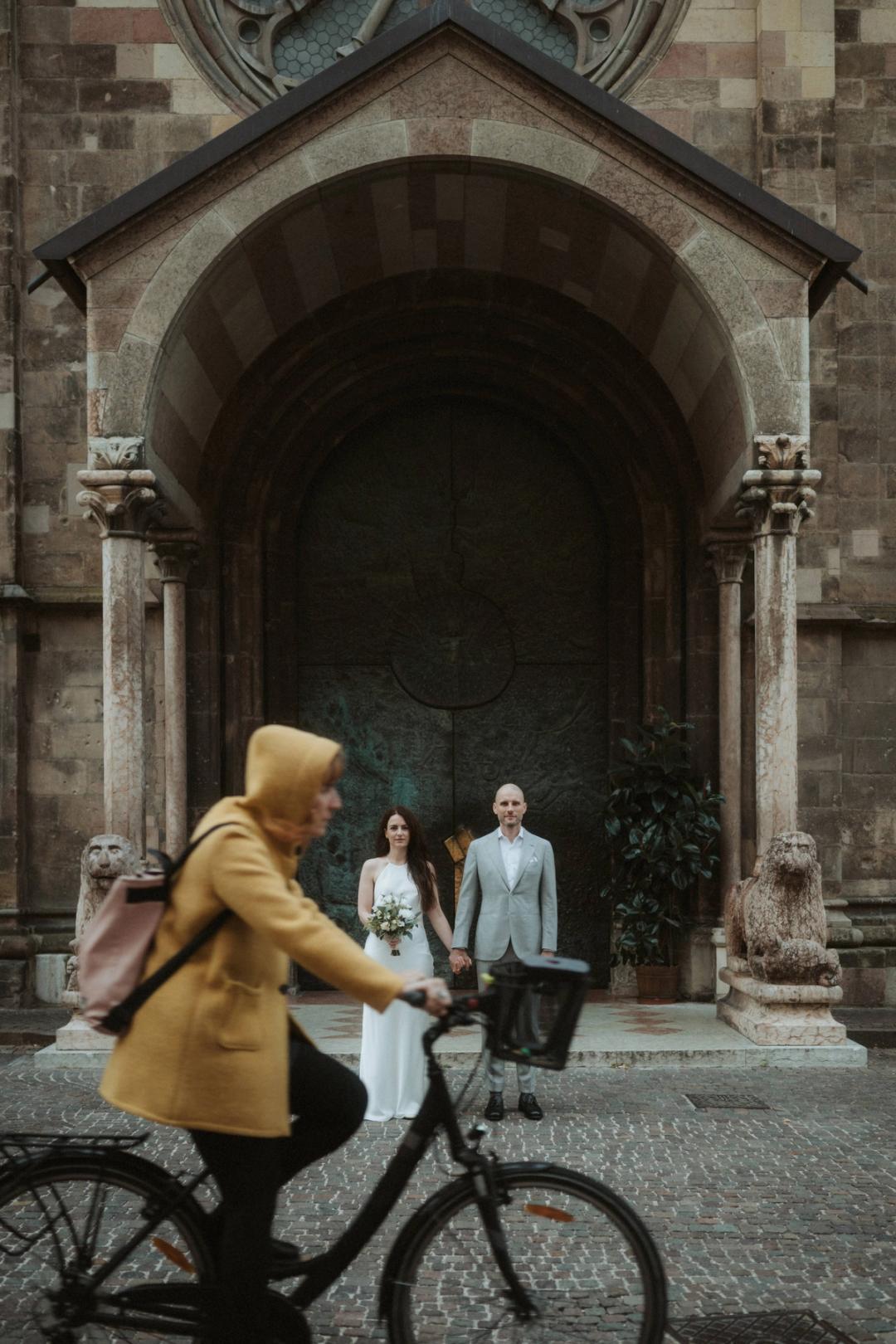 A cyclist crossing the frame in front of Jana and Steffen by a church.