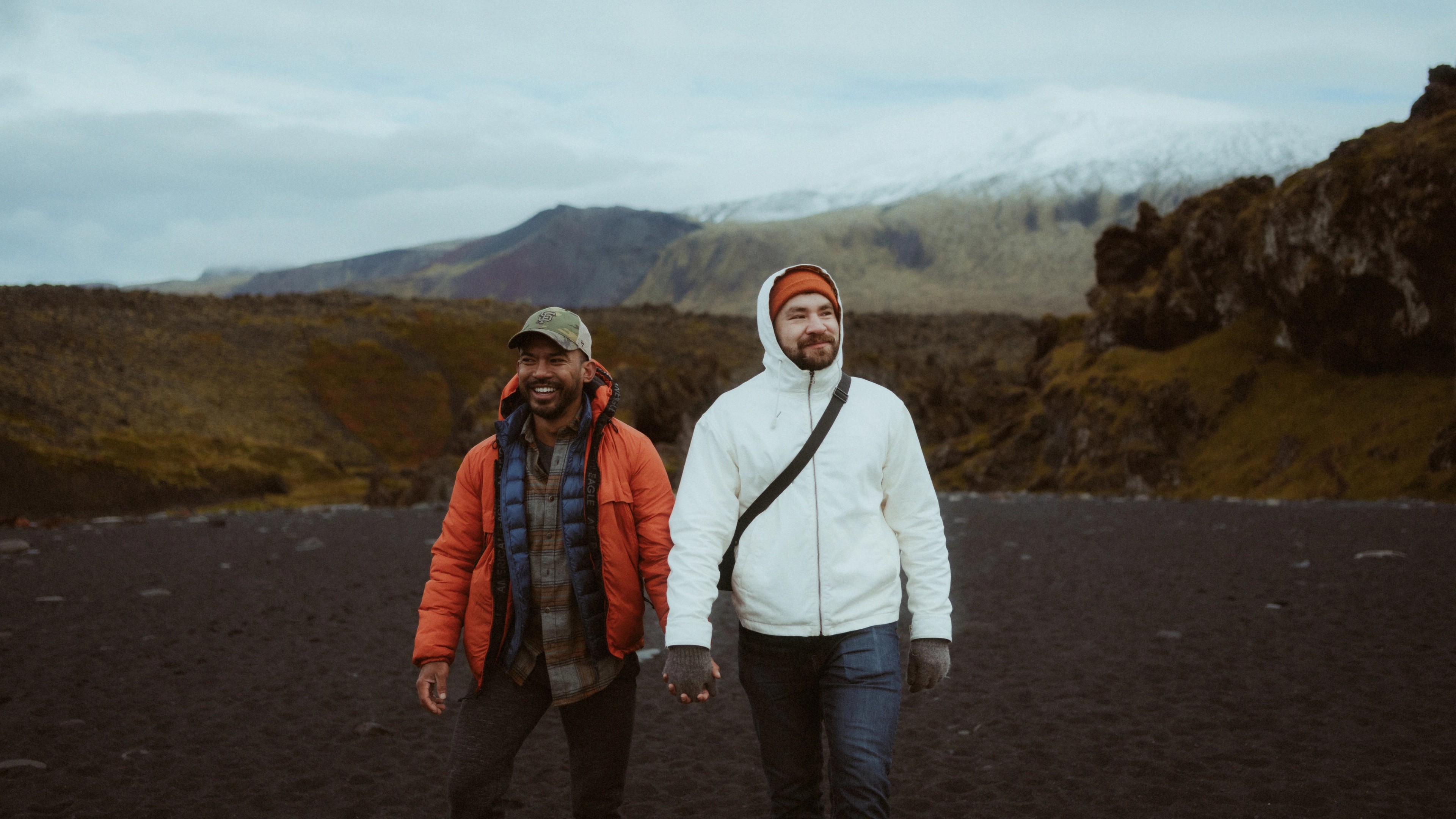 Kris and Ilya laugh while walking back from the rough sea across the black-stone beach.