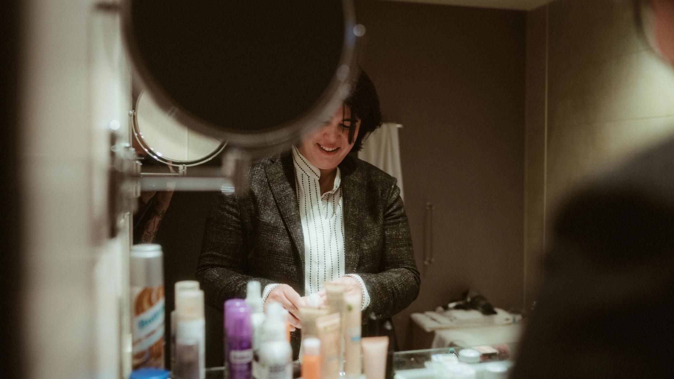 Pia laughing through a circular bathroom mirror