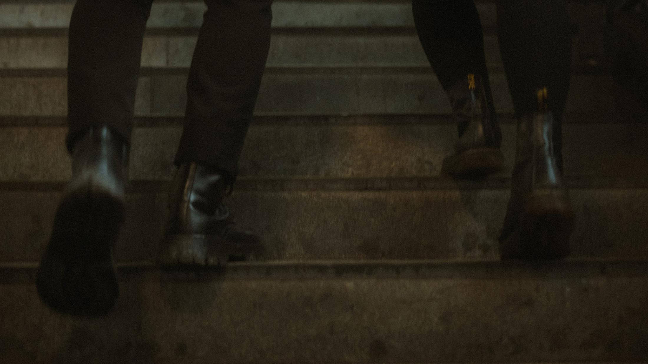 Detail of Lorelai's and Steffen's boots climbing worn station steps.
