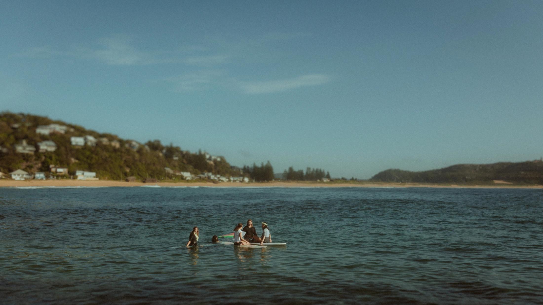 Petra and Roman with their celebrant on surfboards, seen from the Palm Beach shore