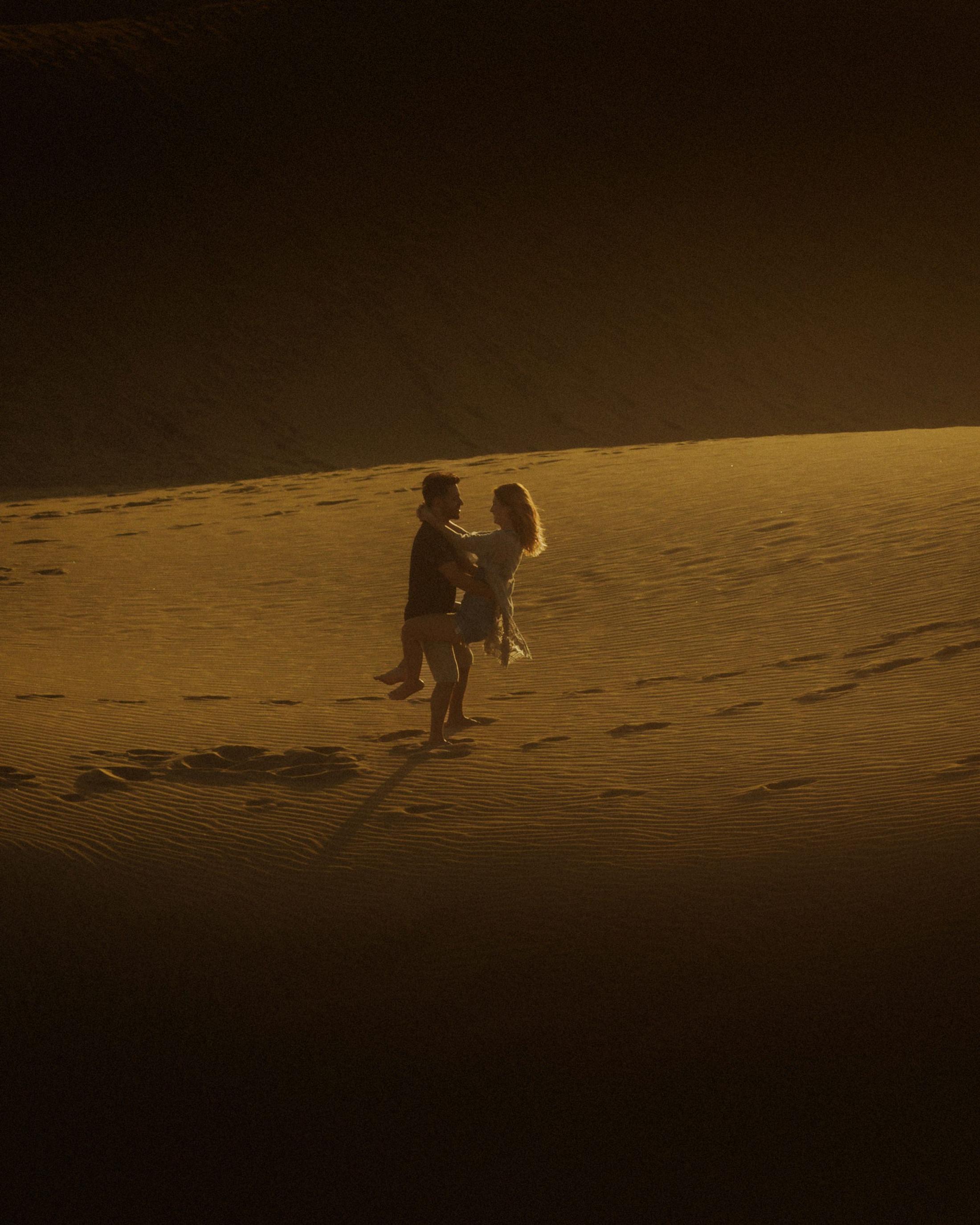 Katja and David standing together inside a vertical band of dune shadow.