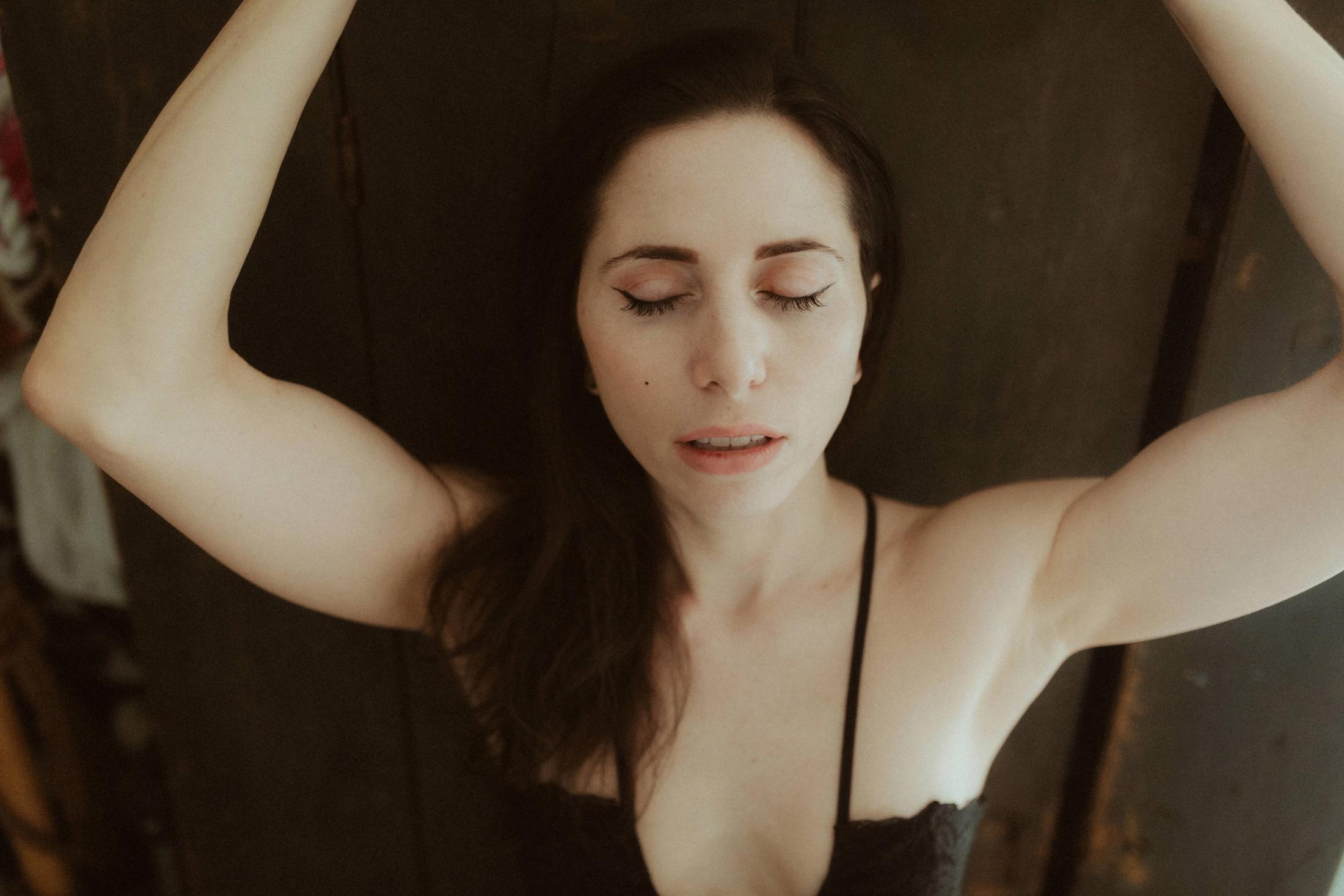Close portrait of Maya with both arms raised and eyes closed.