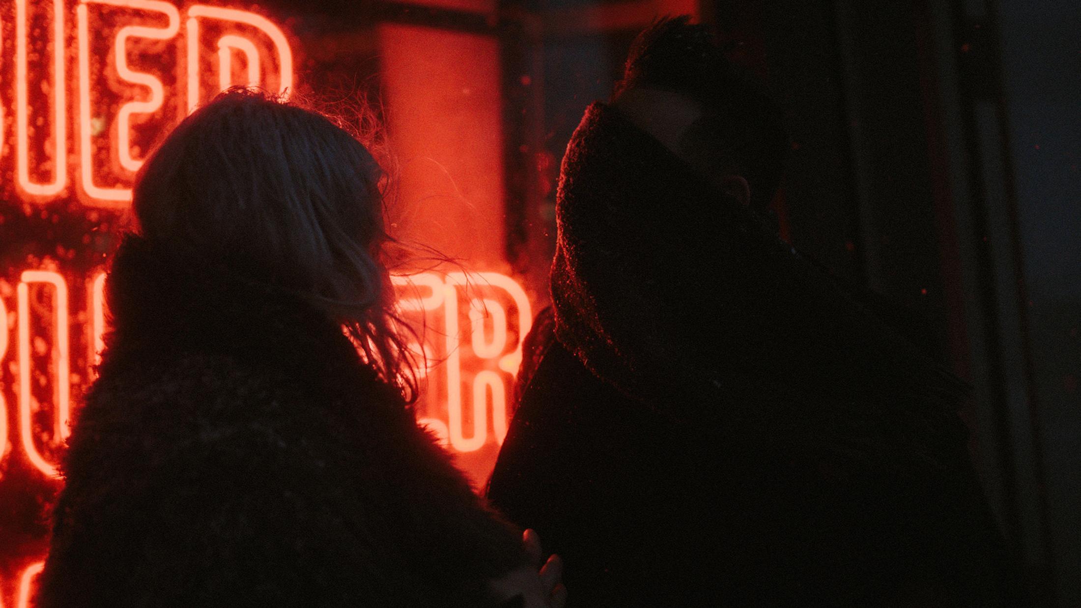 Dark silhouettes of Lorelai and Steffen kissing against red neon light.