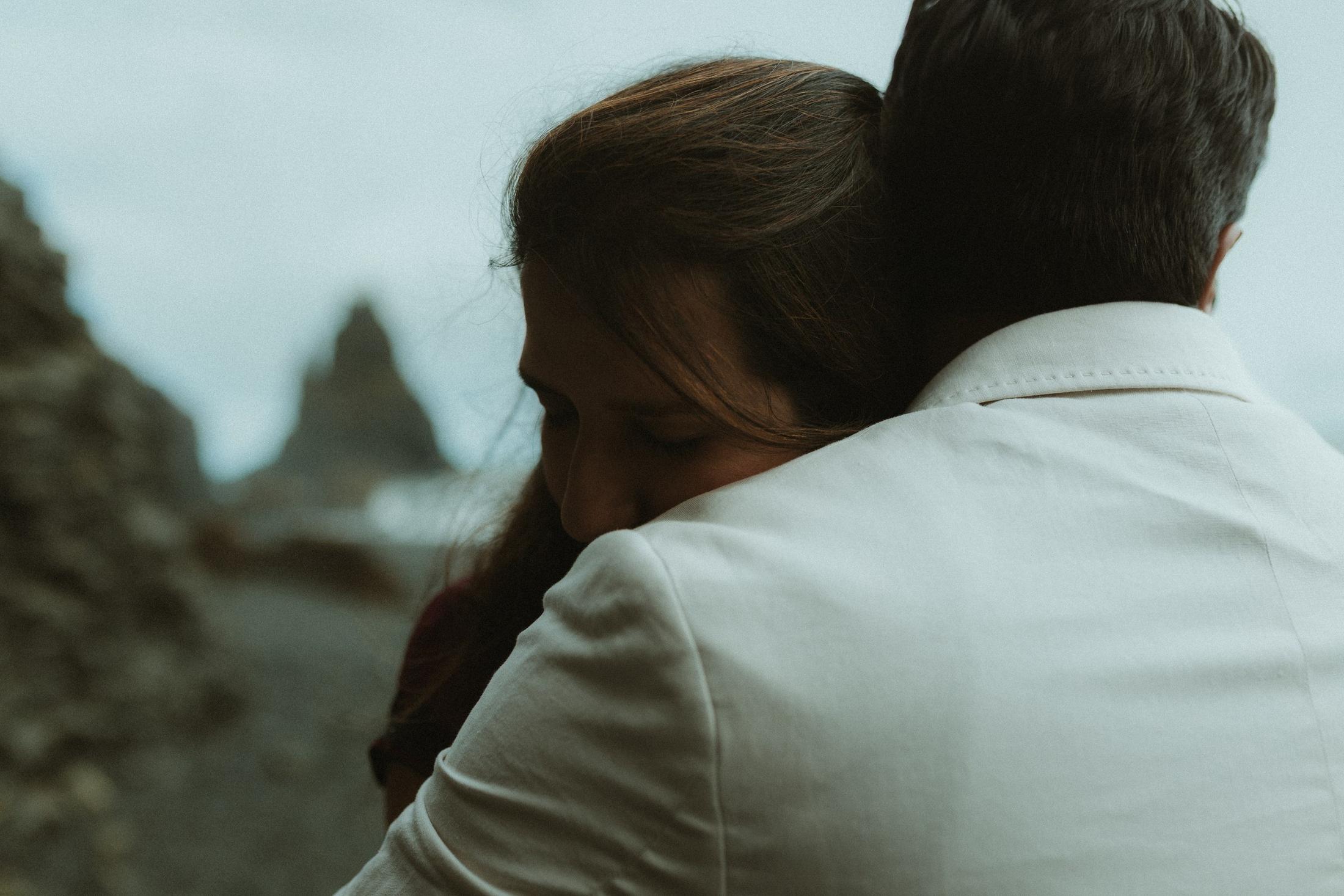 Close portrait of a person resting their face on their partner’s shoulder.