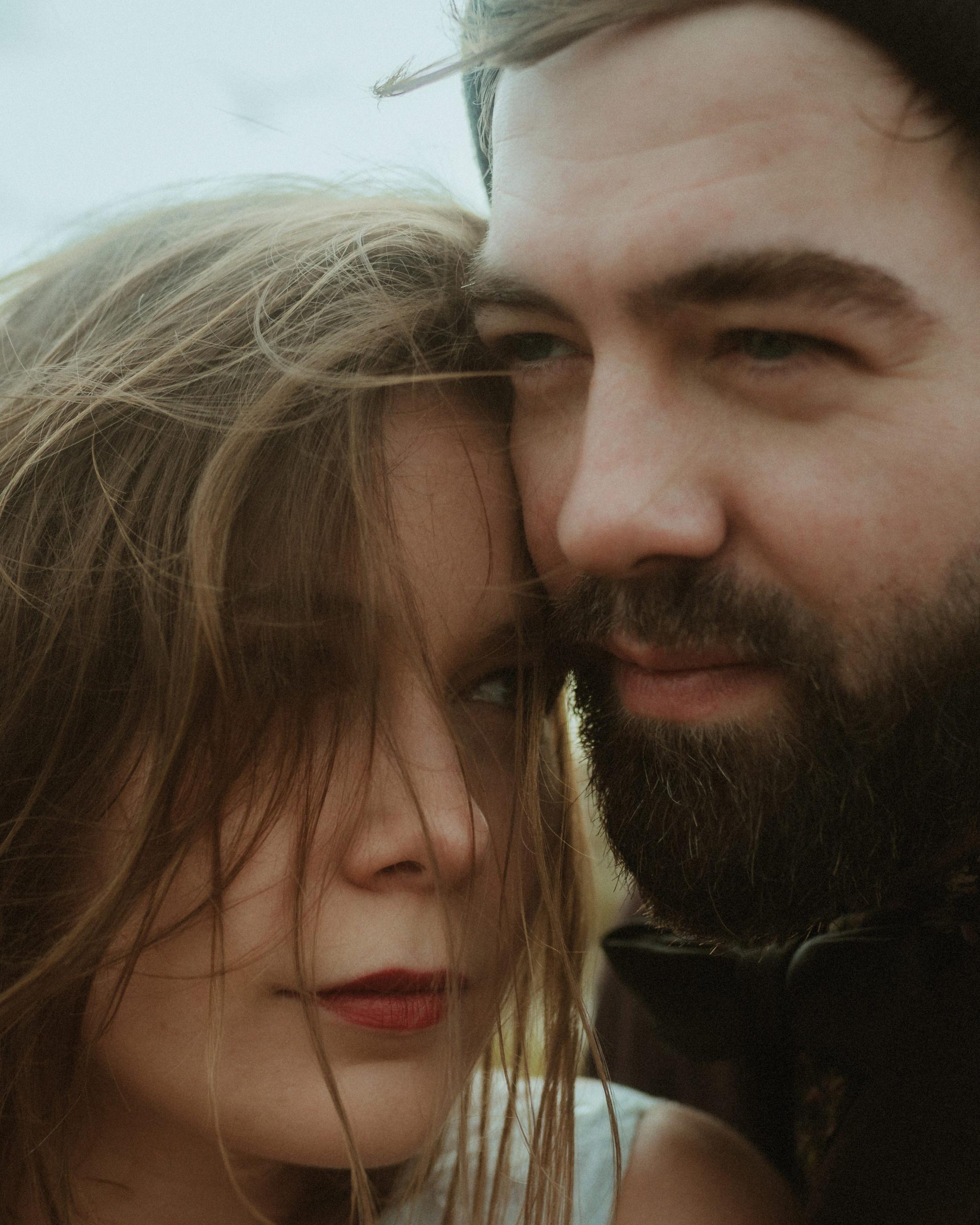 Windswept close portrait of Anni and Daniel with their faces side by side.