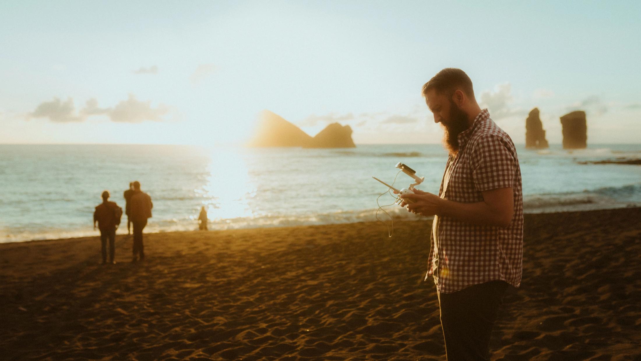 Guests and camera equipment are scattered along the dark beach at dusk.