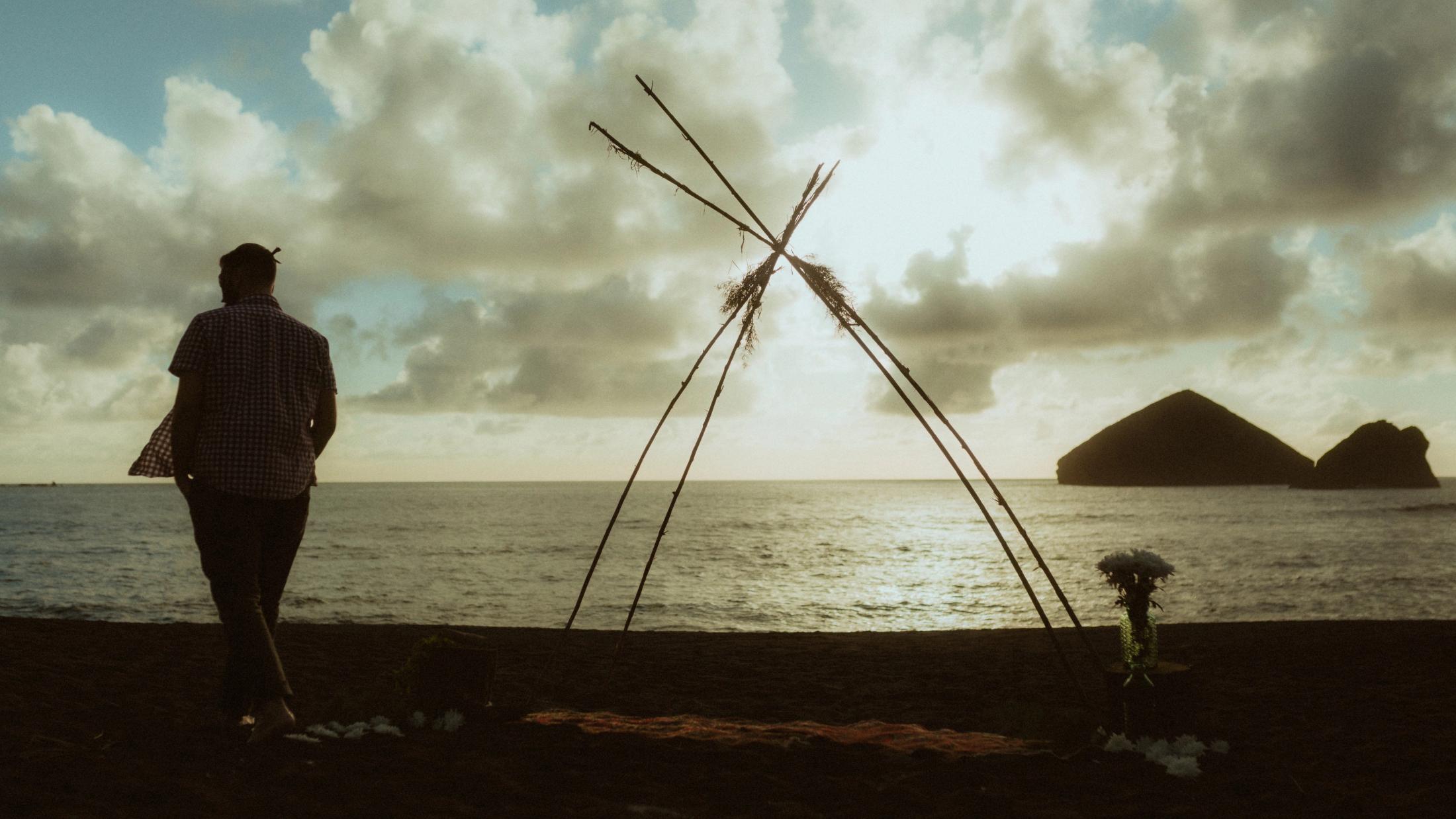 An improvised wedding ceremony structure stands on the beach beside the Atlantic.