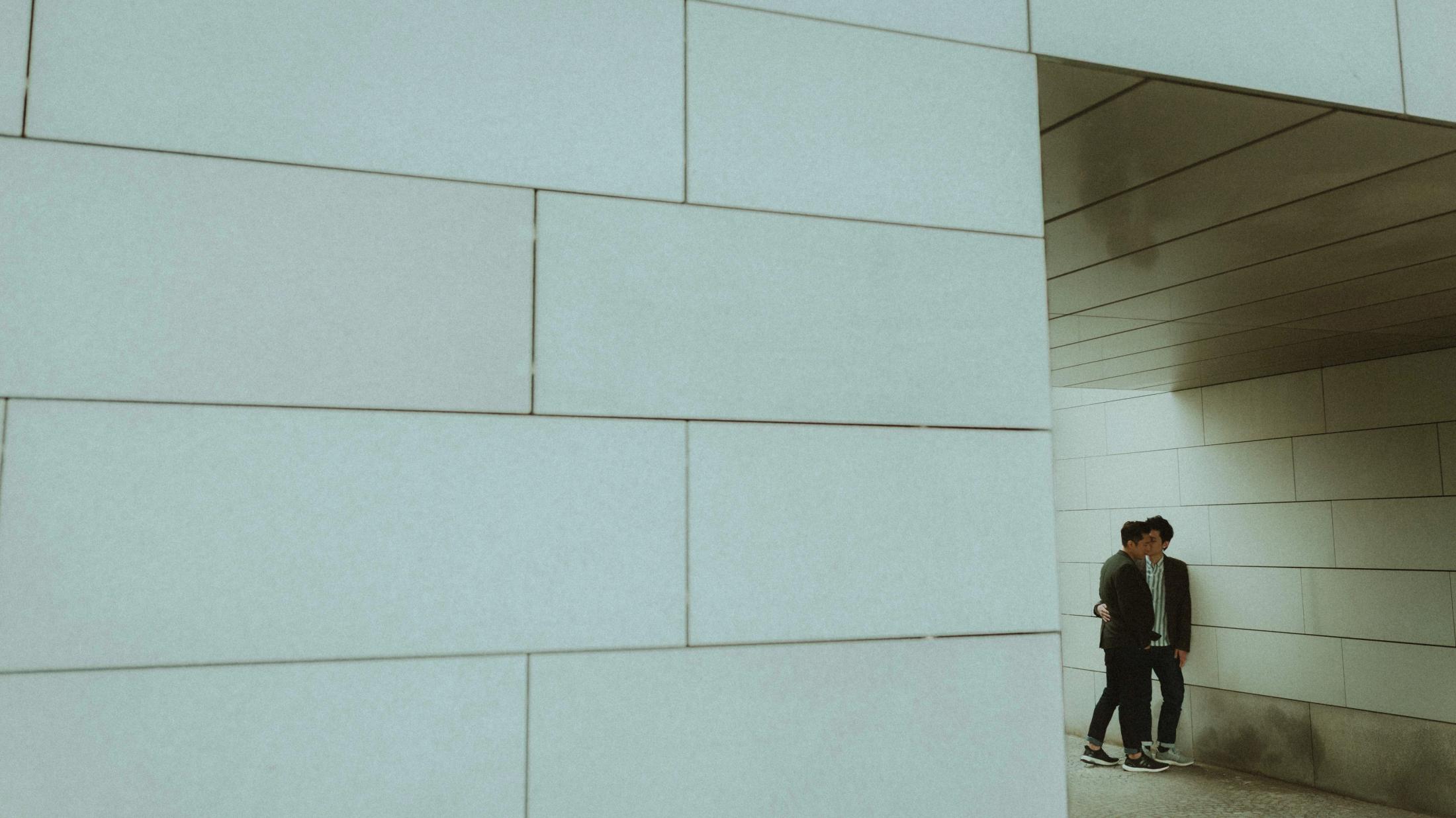 Kevin and Terence stand beneath the geometric facade of a modern Copenhagen building.