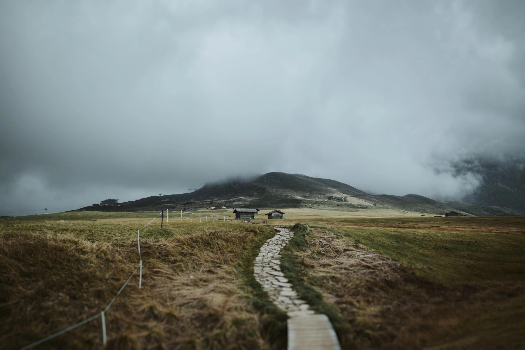 An empty wooden boardwalk beneath low moving clouds.