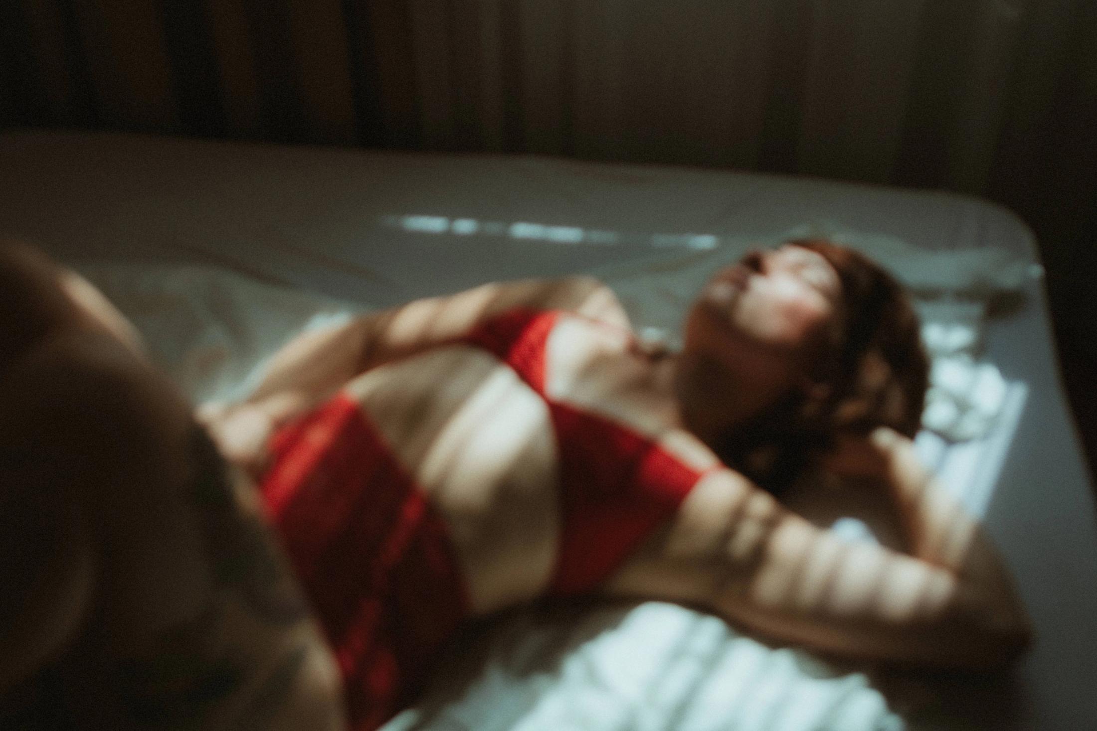 Woman in red lingerie lying in striped window light
