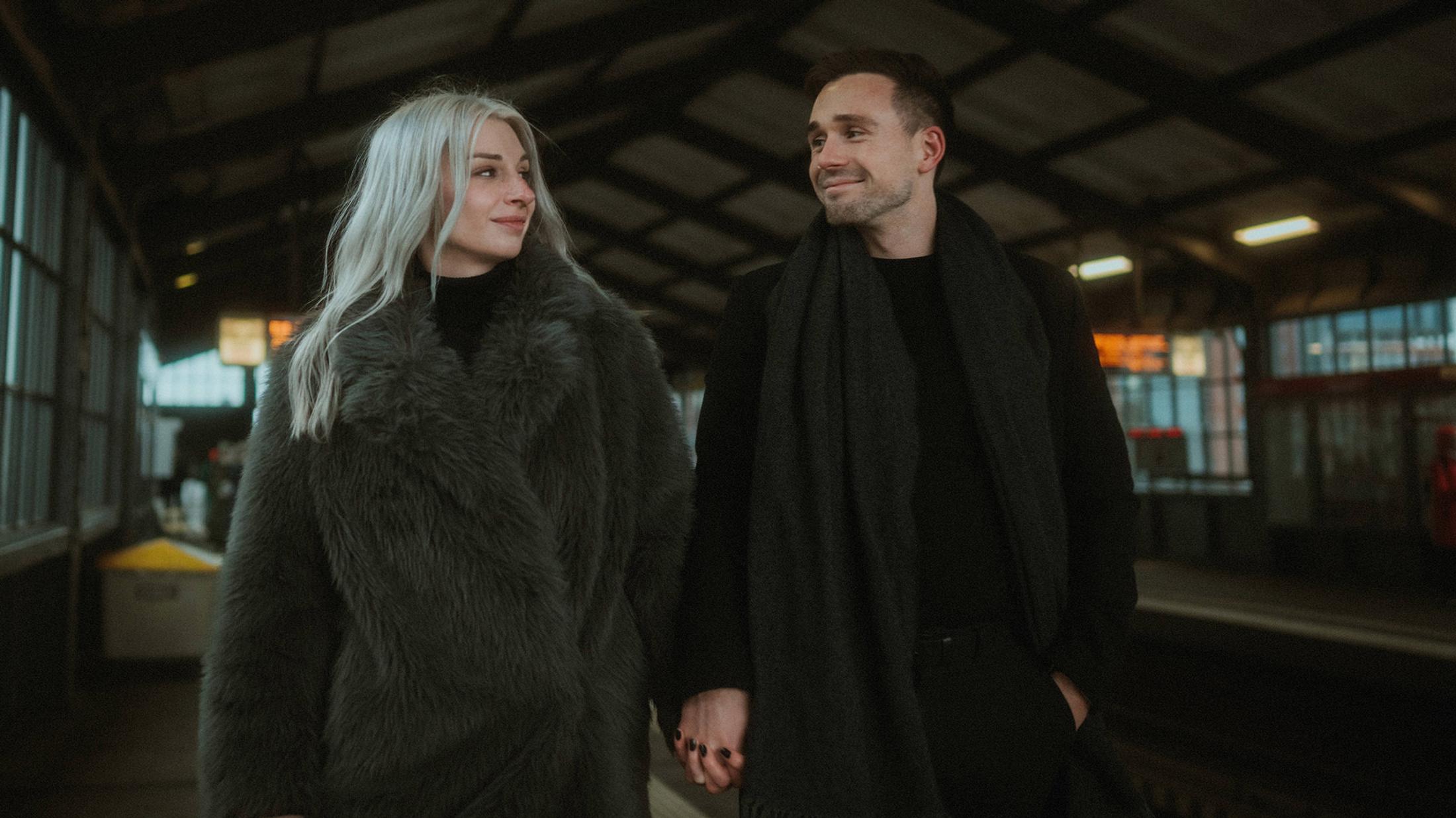 Lorelai and Steffen walk hand in hand along the station platform.