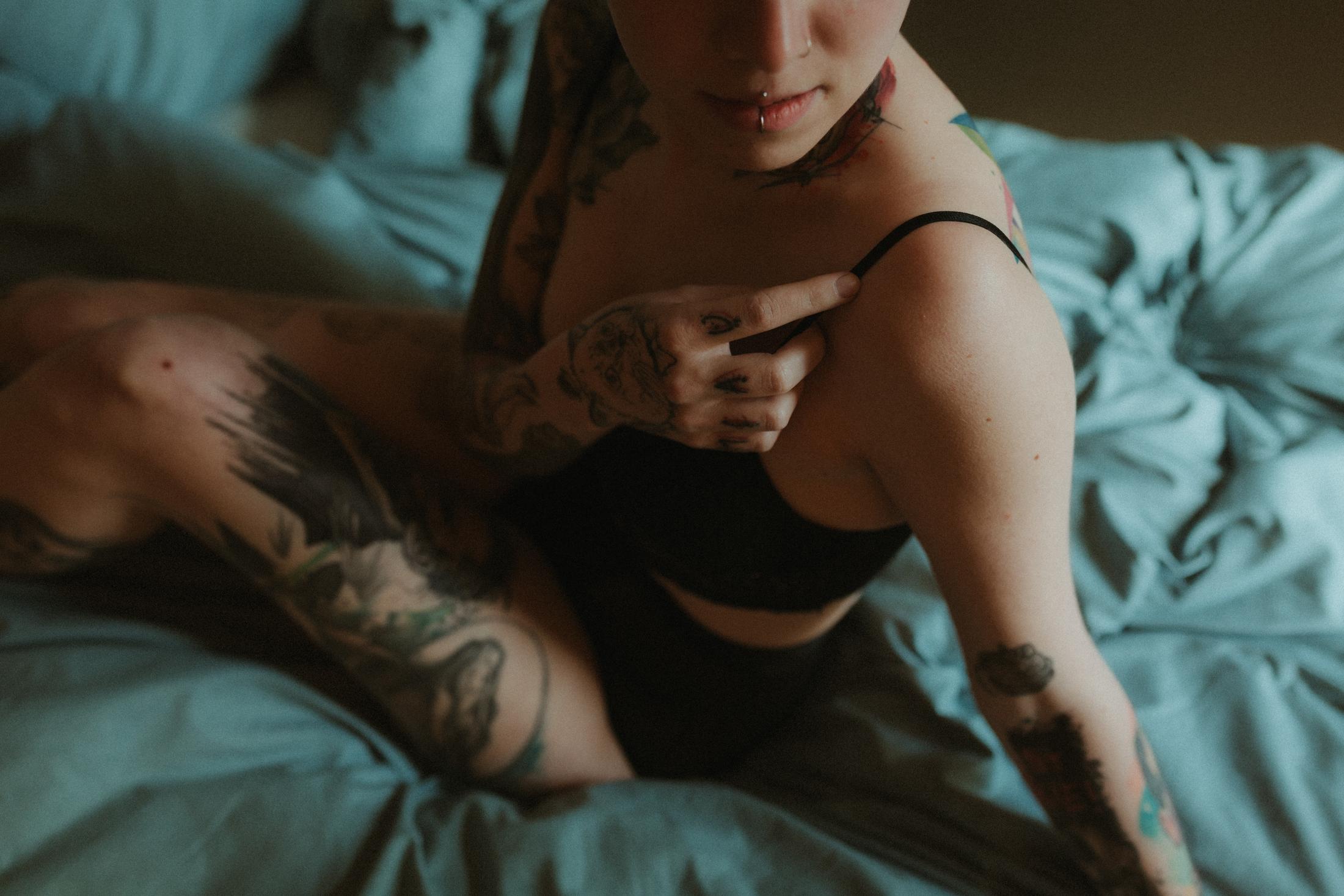 Anki sits on the bed with one hand resting on her shoulder.