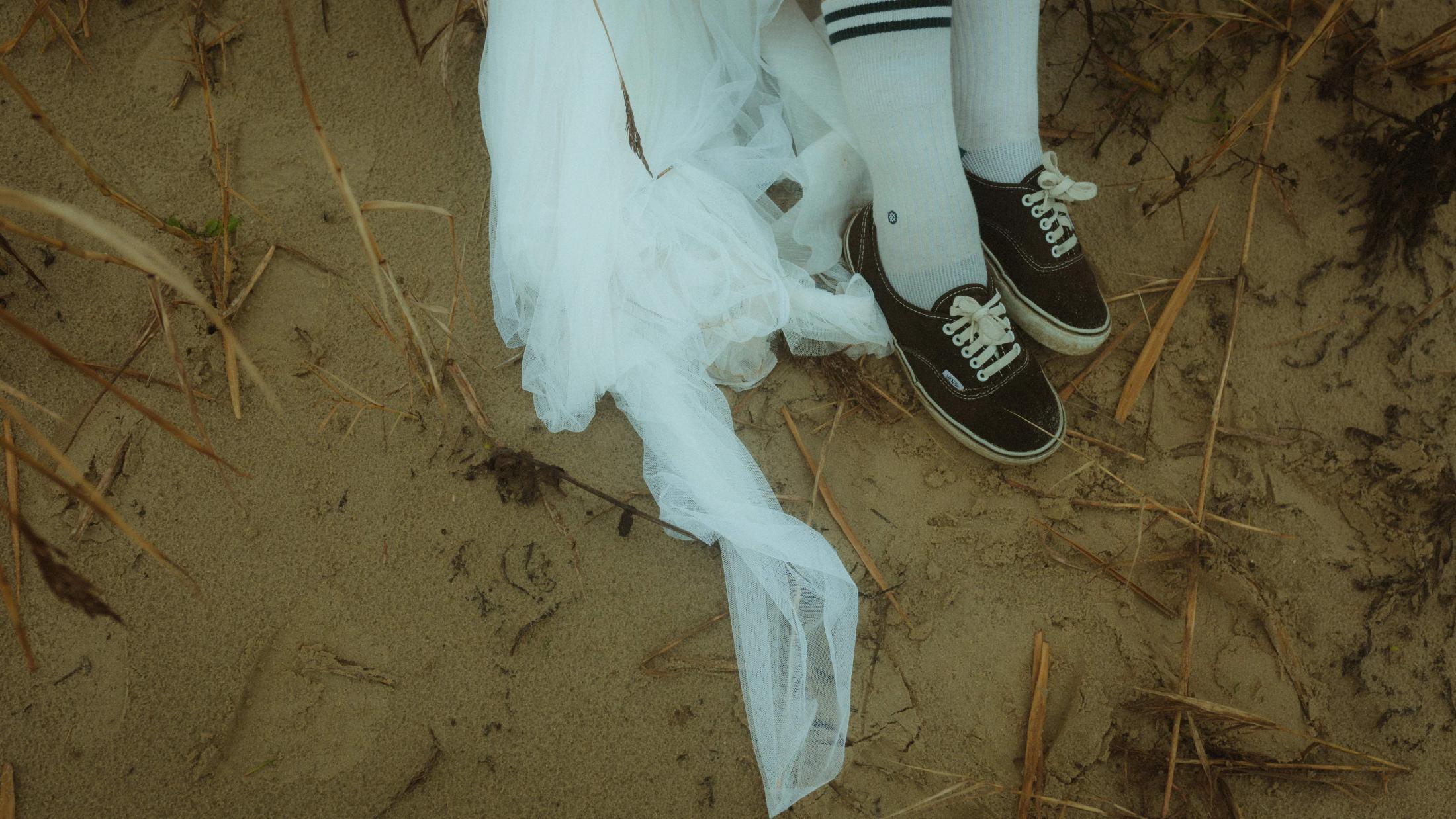 Anni's socks and Daniel's black Vans rest together in the sand.