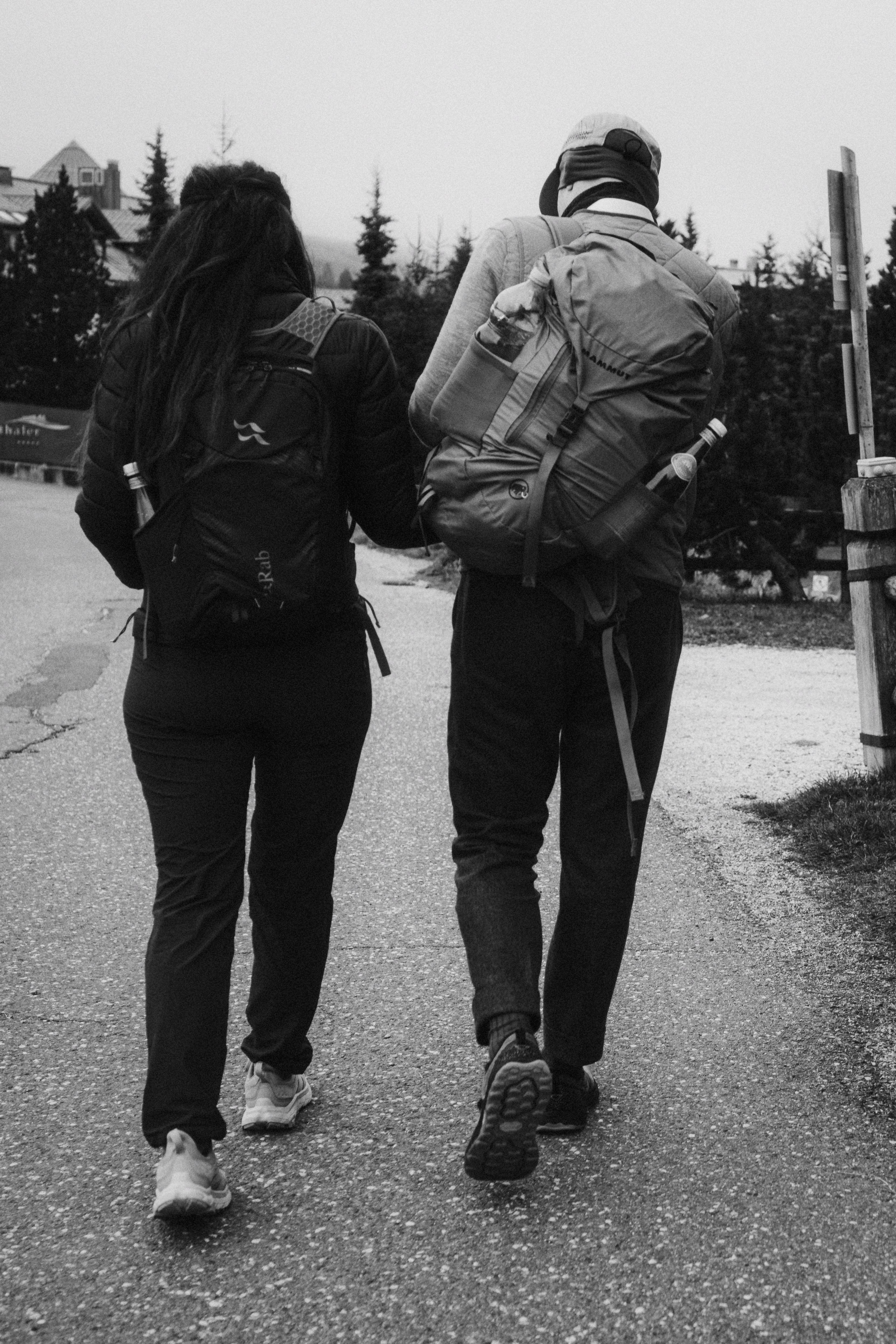 Jana and Steffen walk with backpacks along an alpine trail.