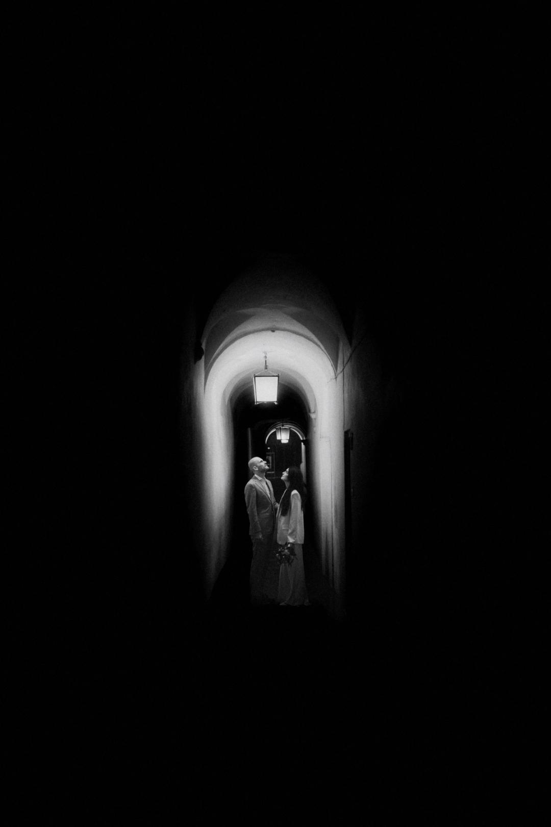 Jana and Steffen appearing small inside a tall arched passage in Bolzano.