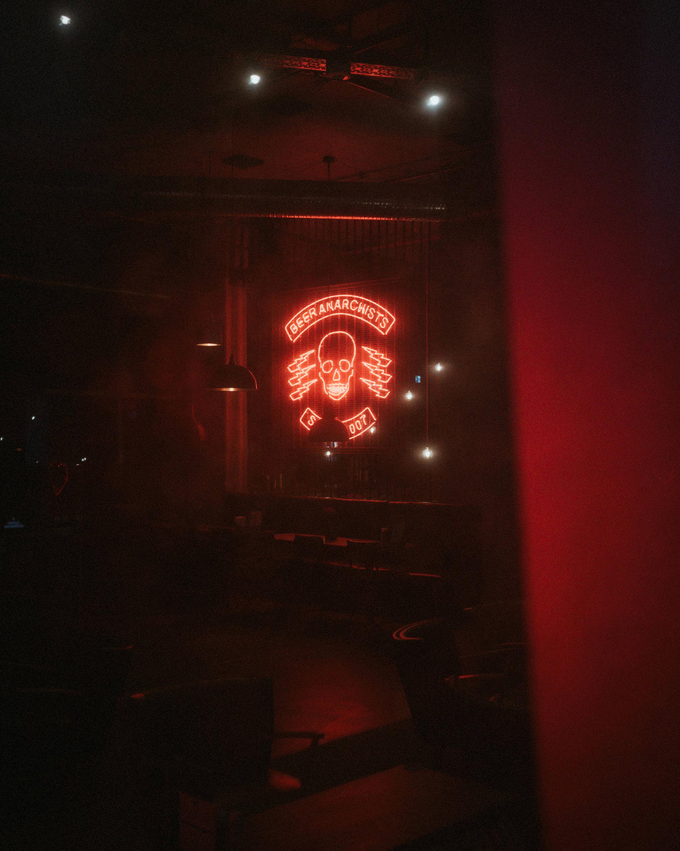 Lorelai and Steffen stand together in a doorway with a distant red neon sign.