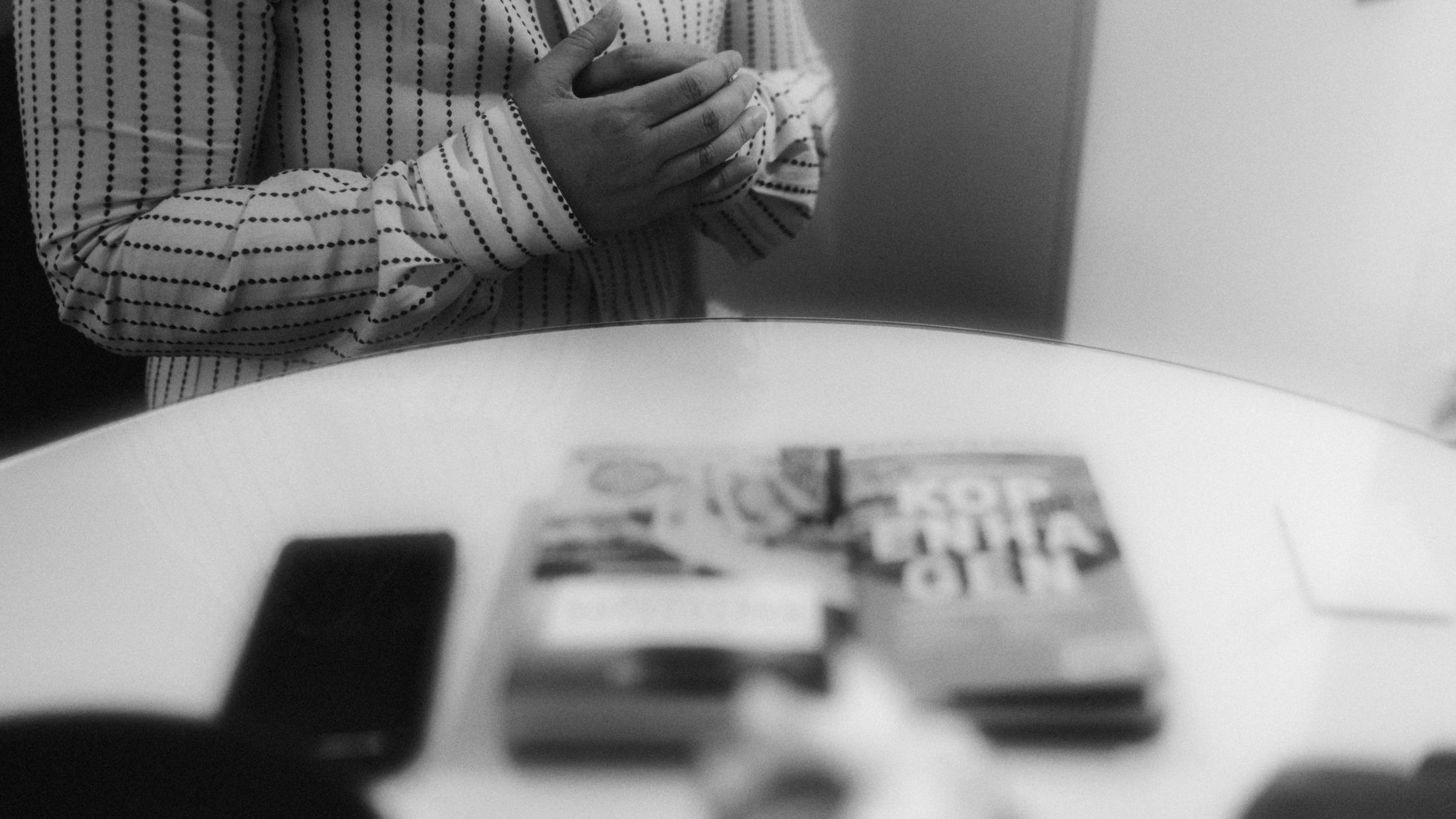 Hands above a blurred table in a black-and-white photograph