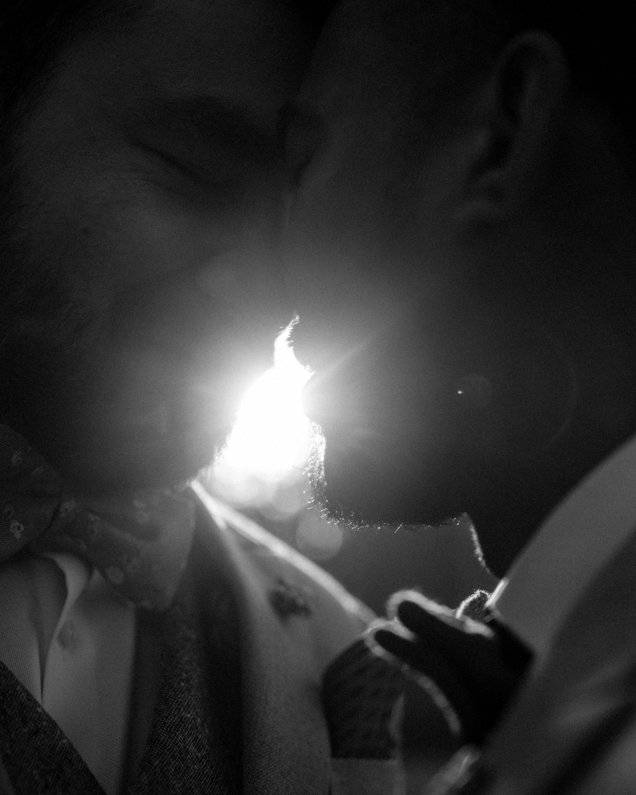 Abstract black-and-white close-up of the couple kissing behind a bright flare.