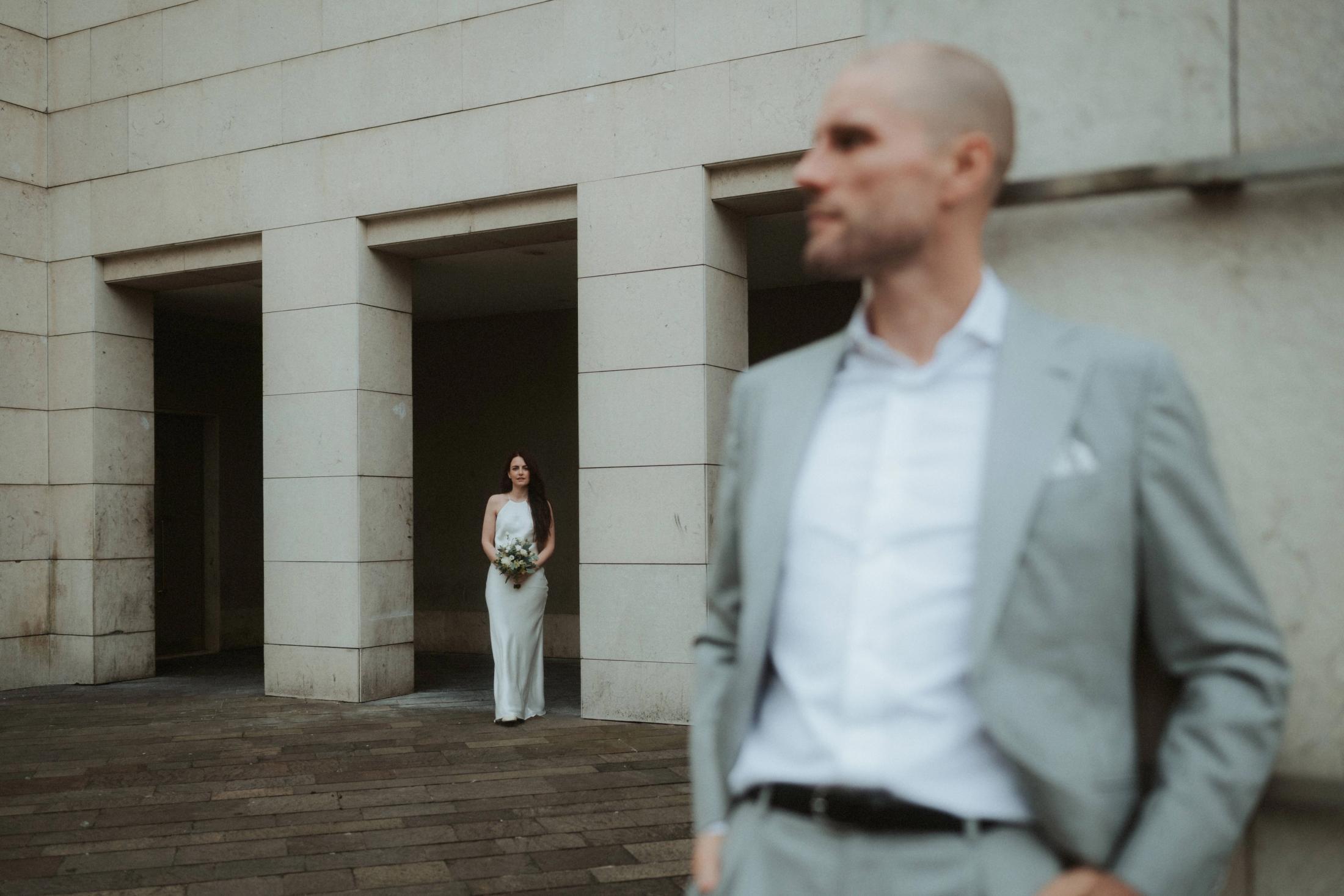 Jana standing apart from Steffen in a graphic architectural composition.