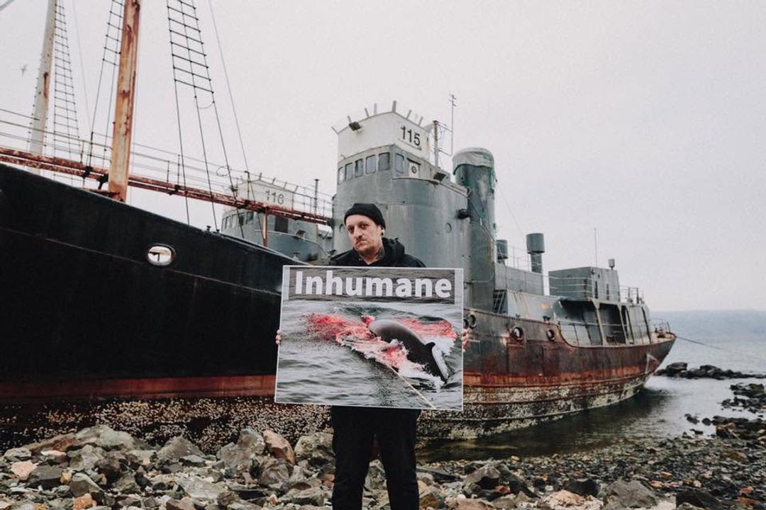 Bjørn holds an Inhumane placard in front of an old whaling ship in Iceland.
