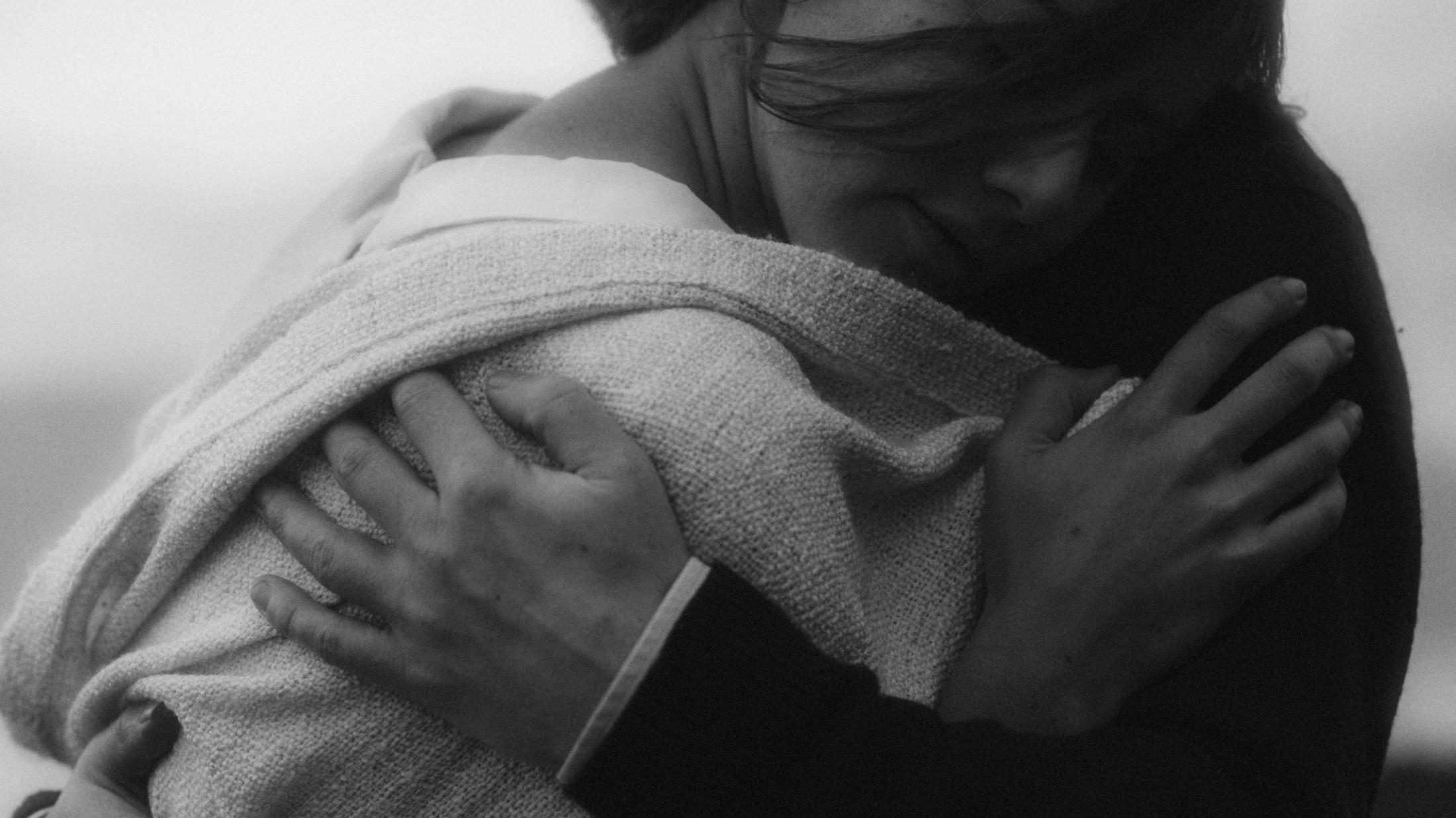 Jule and Rory hold each other in a black-and-white close-up.