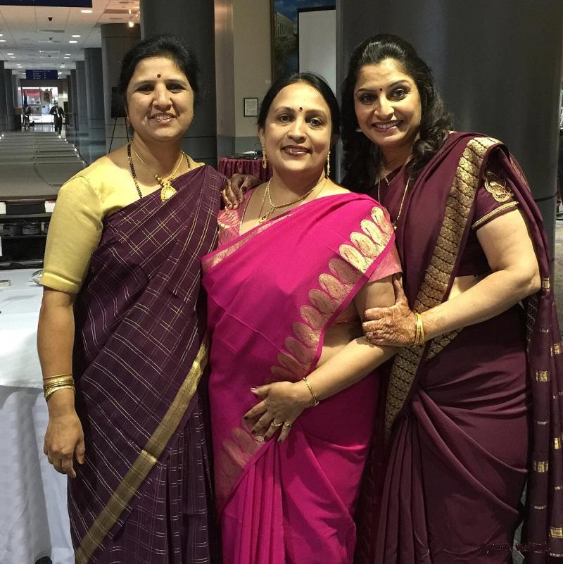 Three women wearing Mysore silk crepe sarees including the signature pink-with-gold-zari