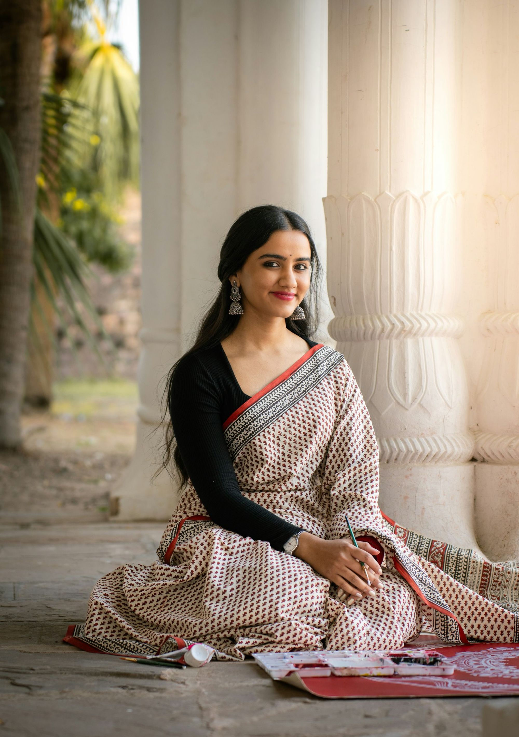A woman in a pastel Chanderi saree by a temple pillar