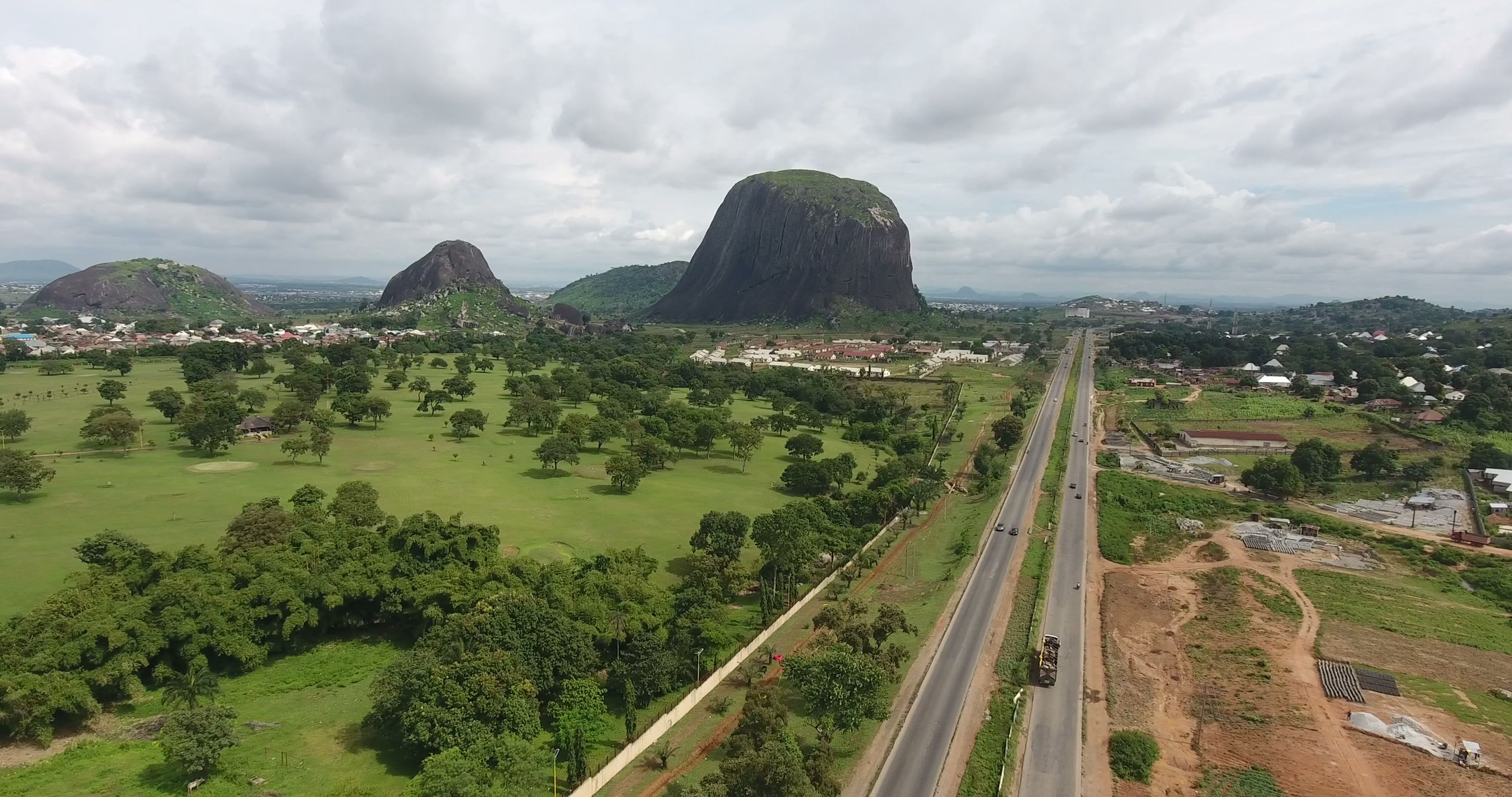 Aerial view of Zuma Rock rising above green countryside beside a highway