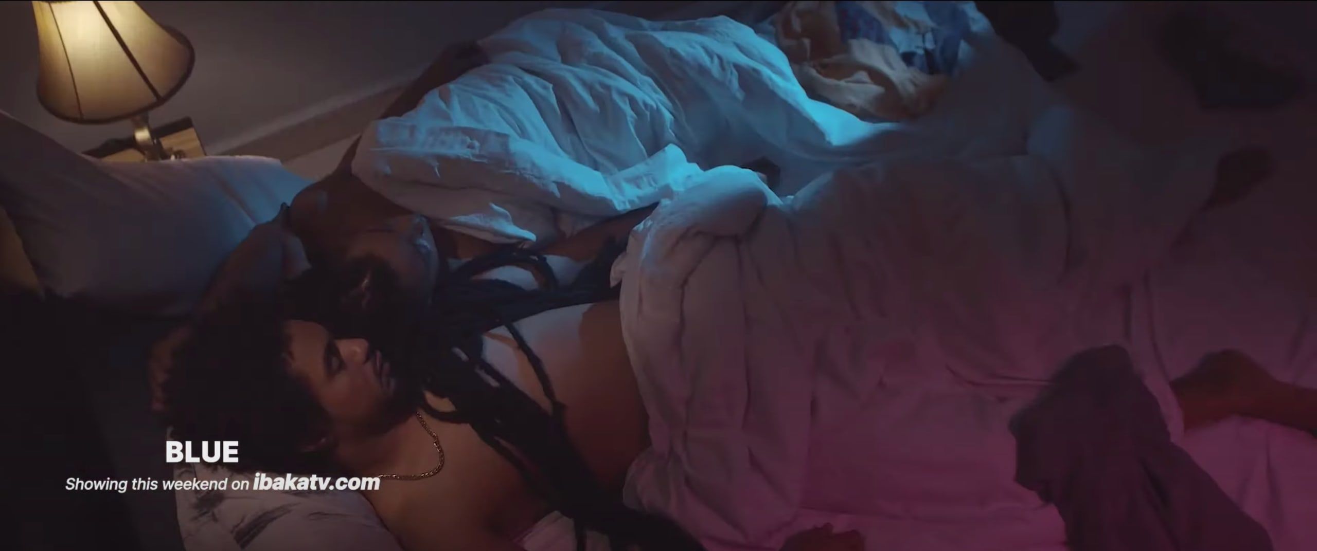 A couple resting under white sheets in dim lamplight, with the title Blue